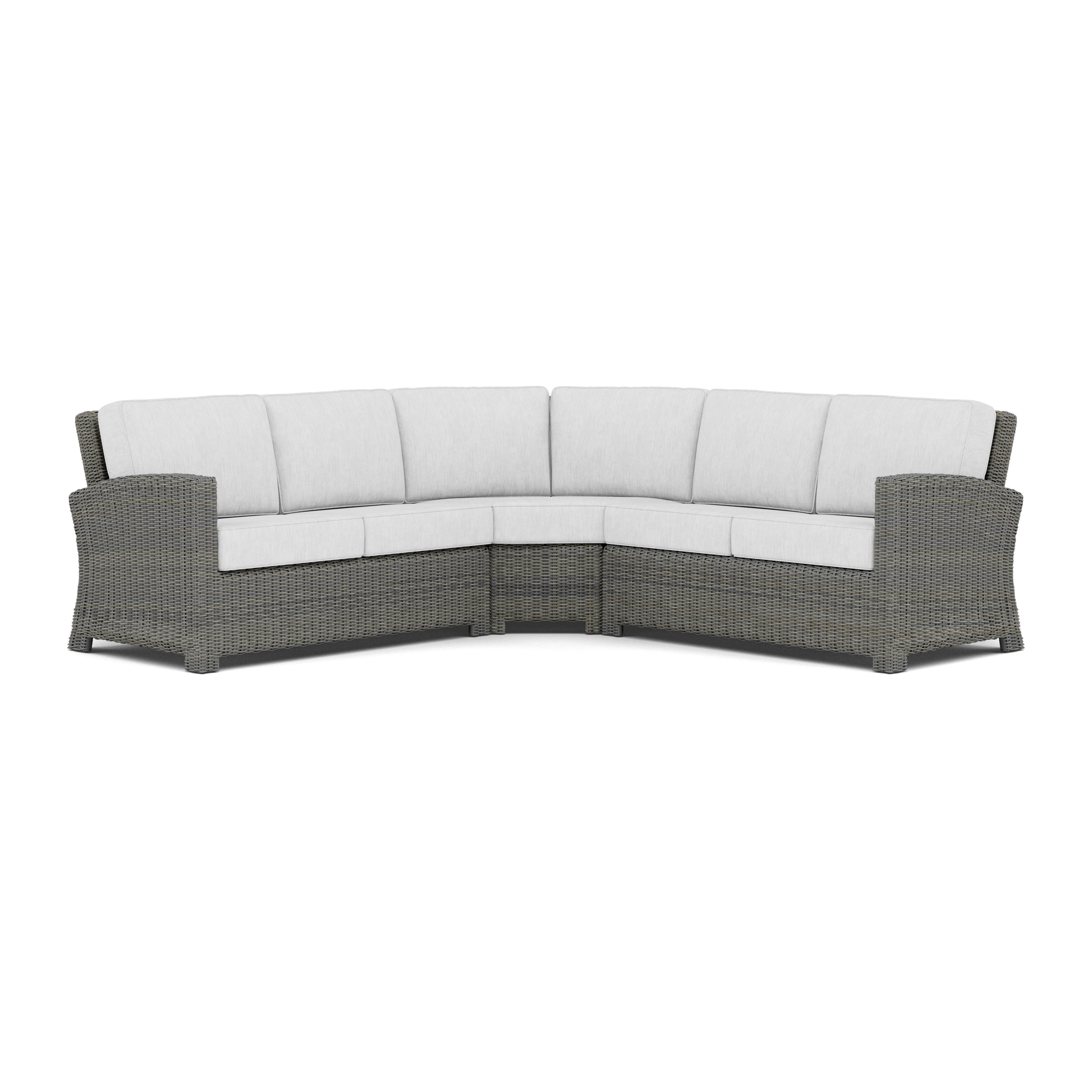 Curved outdoor sectional sofa with light gray cushions and woven rattan frame.
