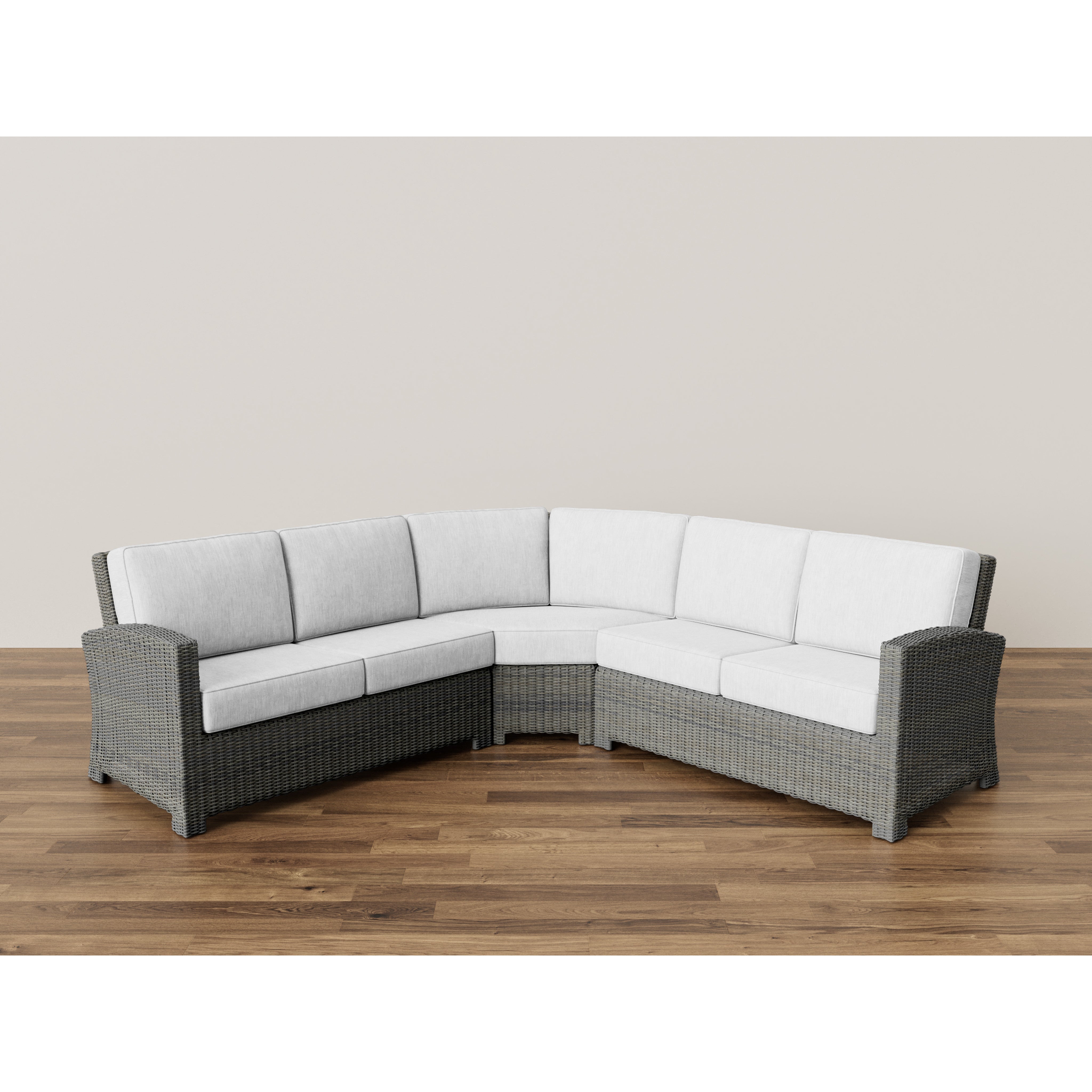 Gray wicker L-shaped sectional sofa with white cushions on a wood floor.