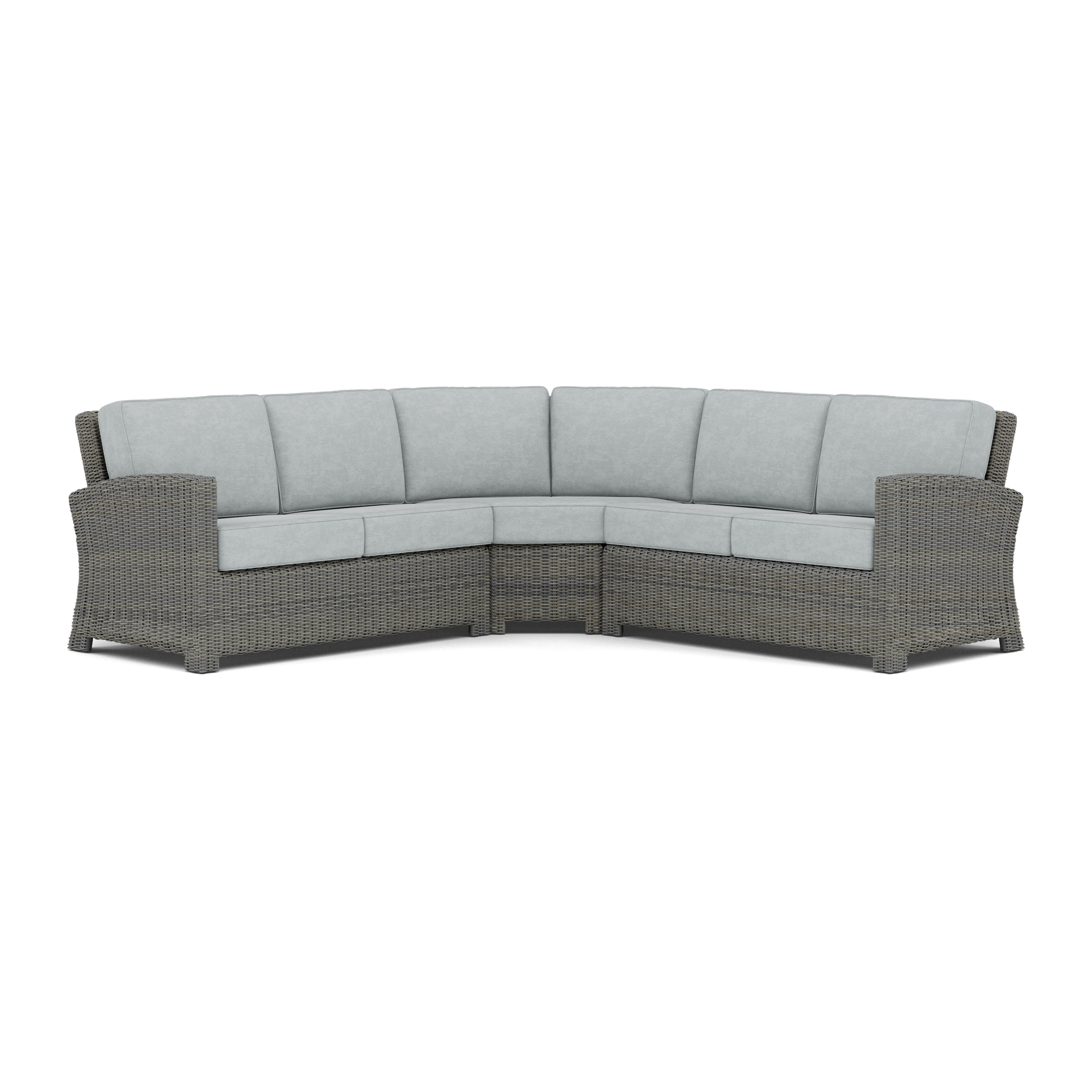 Curved outdoor sectional sofa with gray wicker frame and light gray cushions.