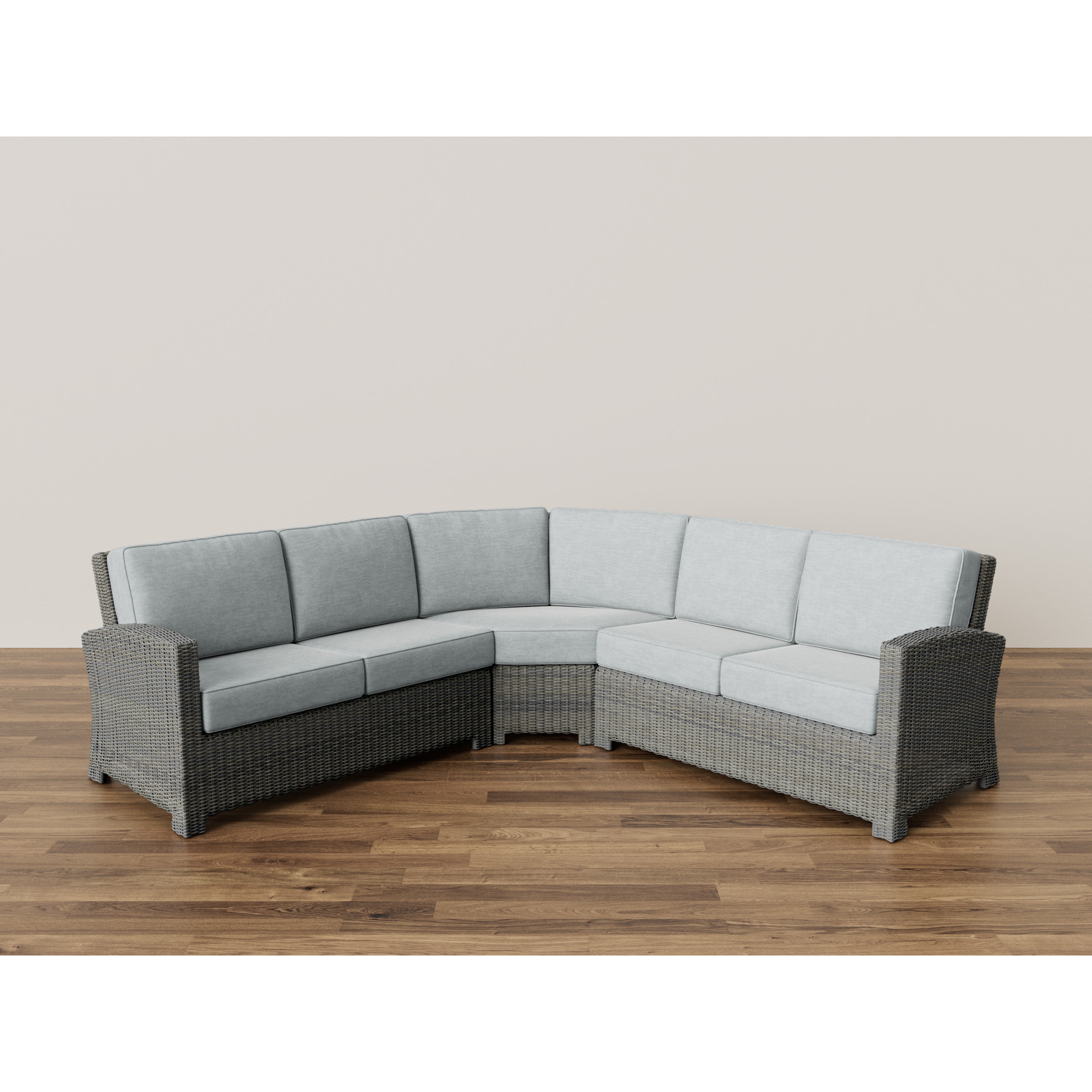 Gray wicker sectional sofa with light gray cushions on wood floor.