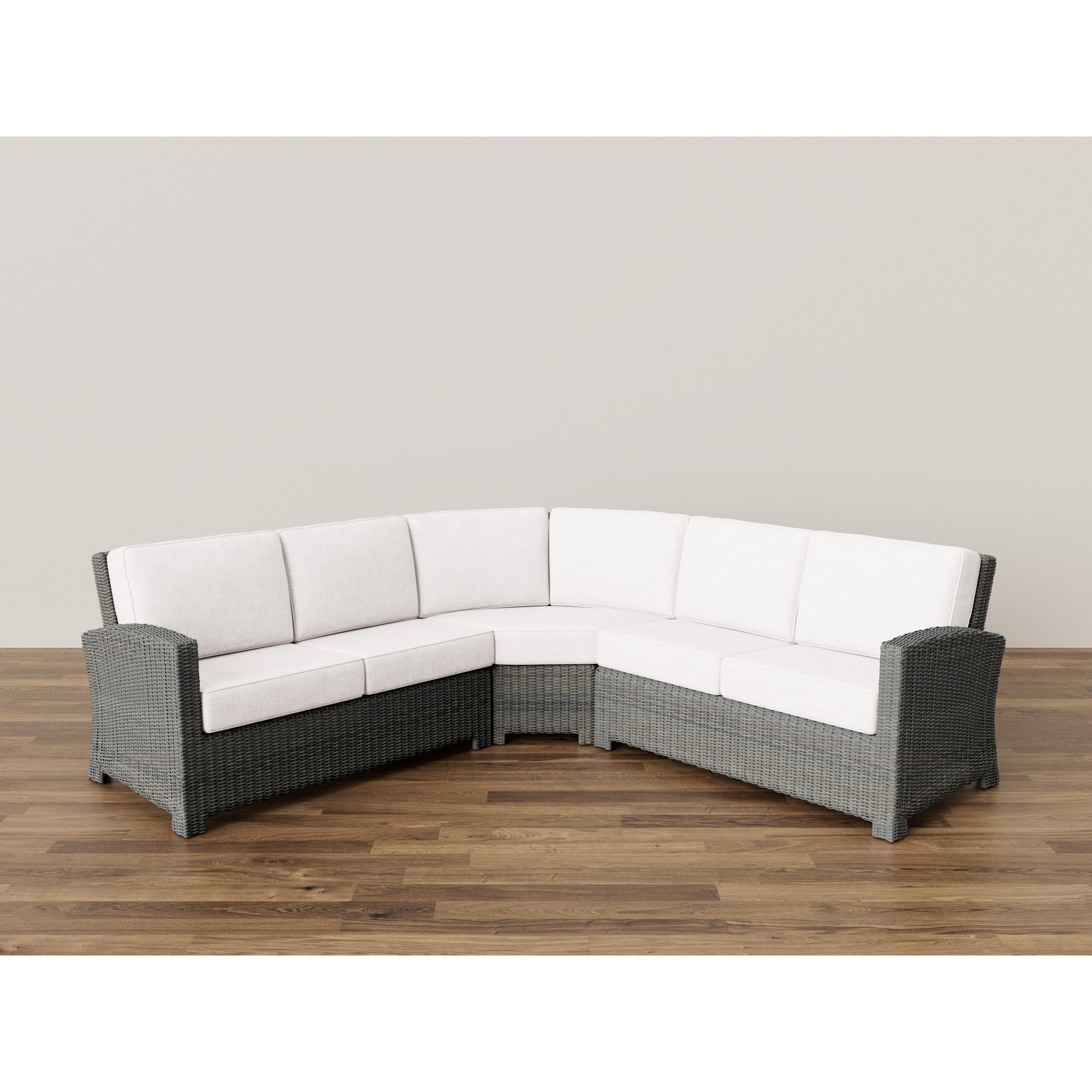 Gray wicker L-shaped sectional sofa with white cushions on wood floor.