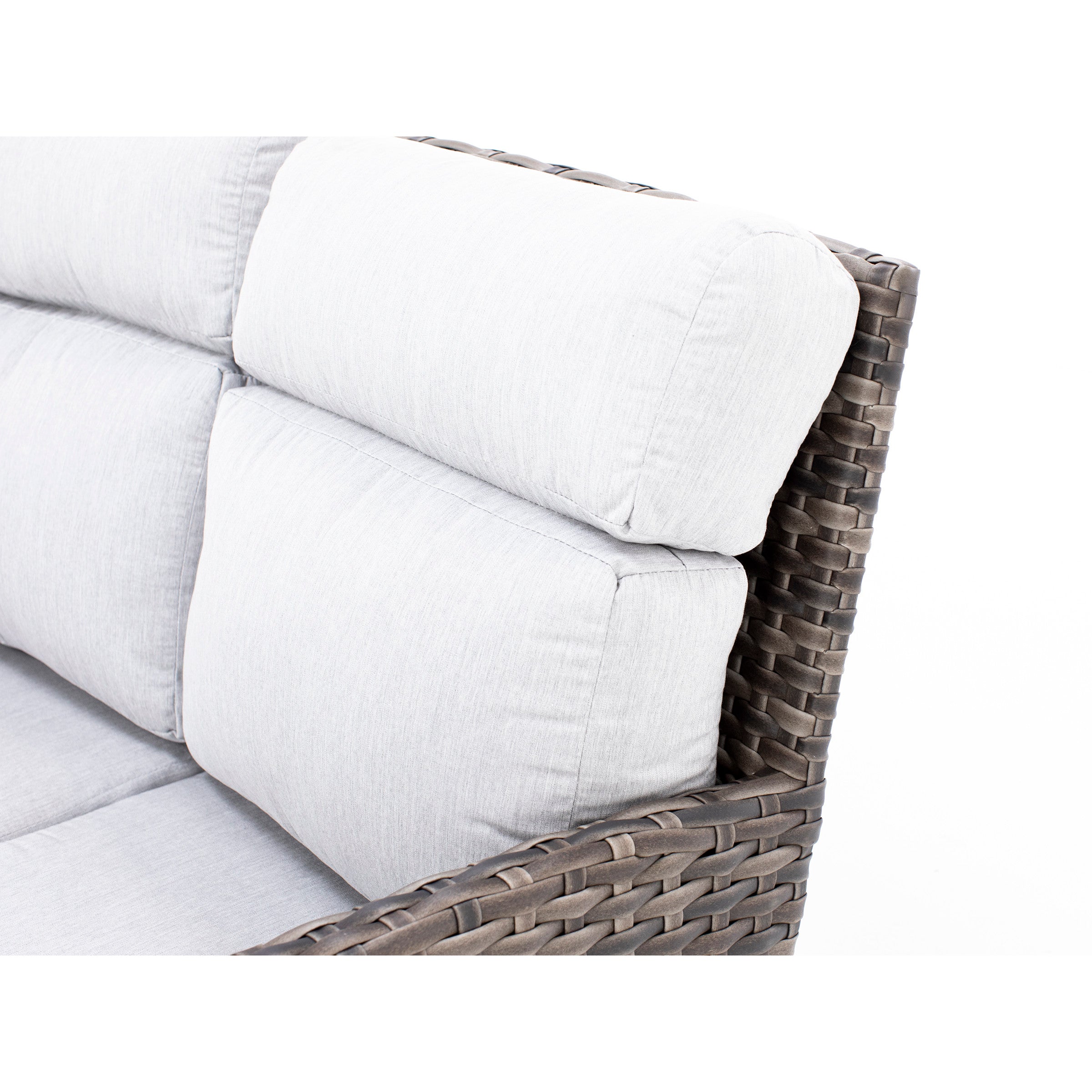 Close-up of a woven outdoor chair with thick, light gray cushions.