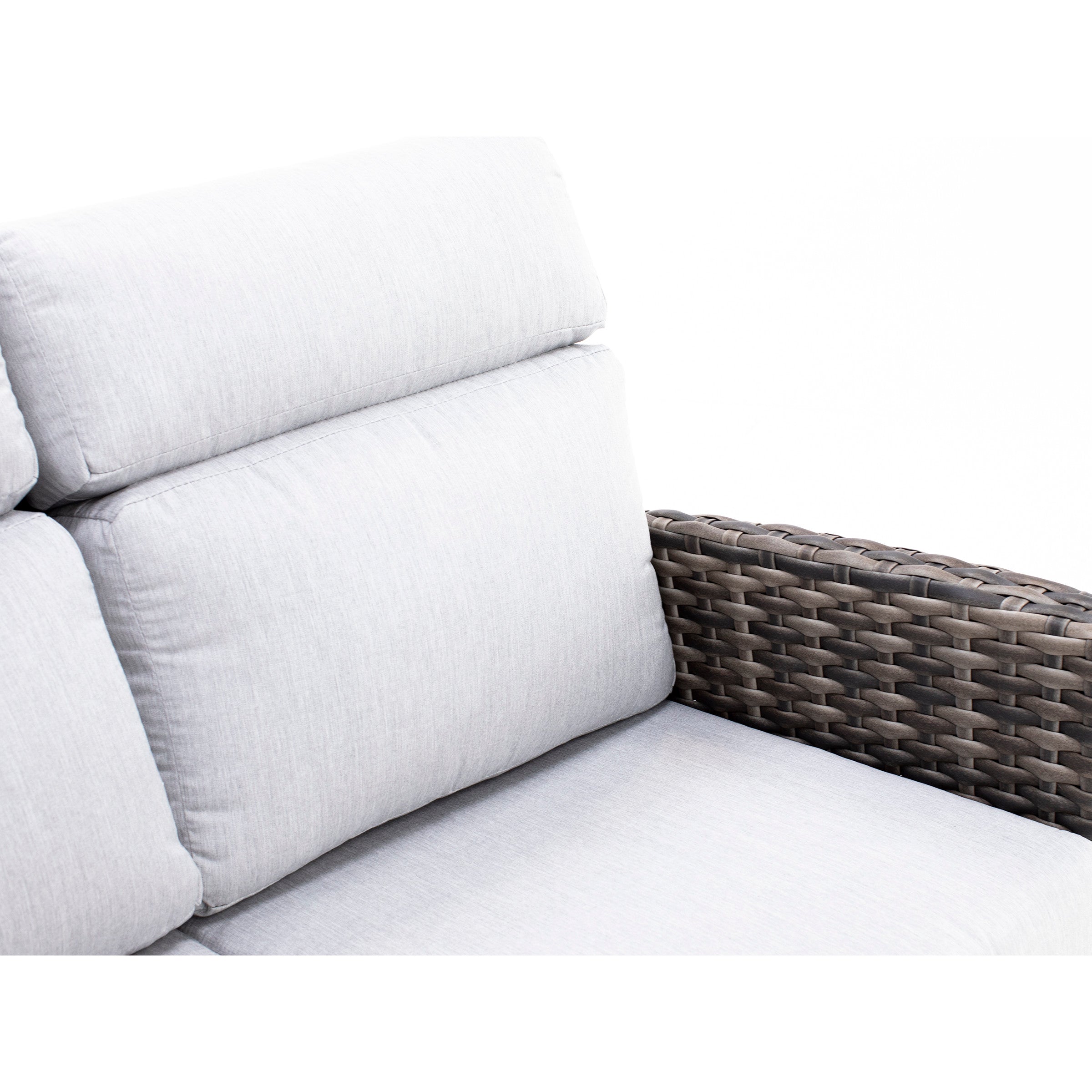Close-up of a light gray cushioned chair with woven wicker armrest.