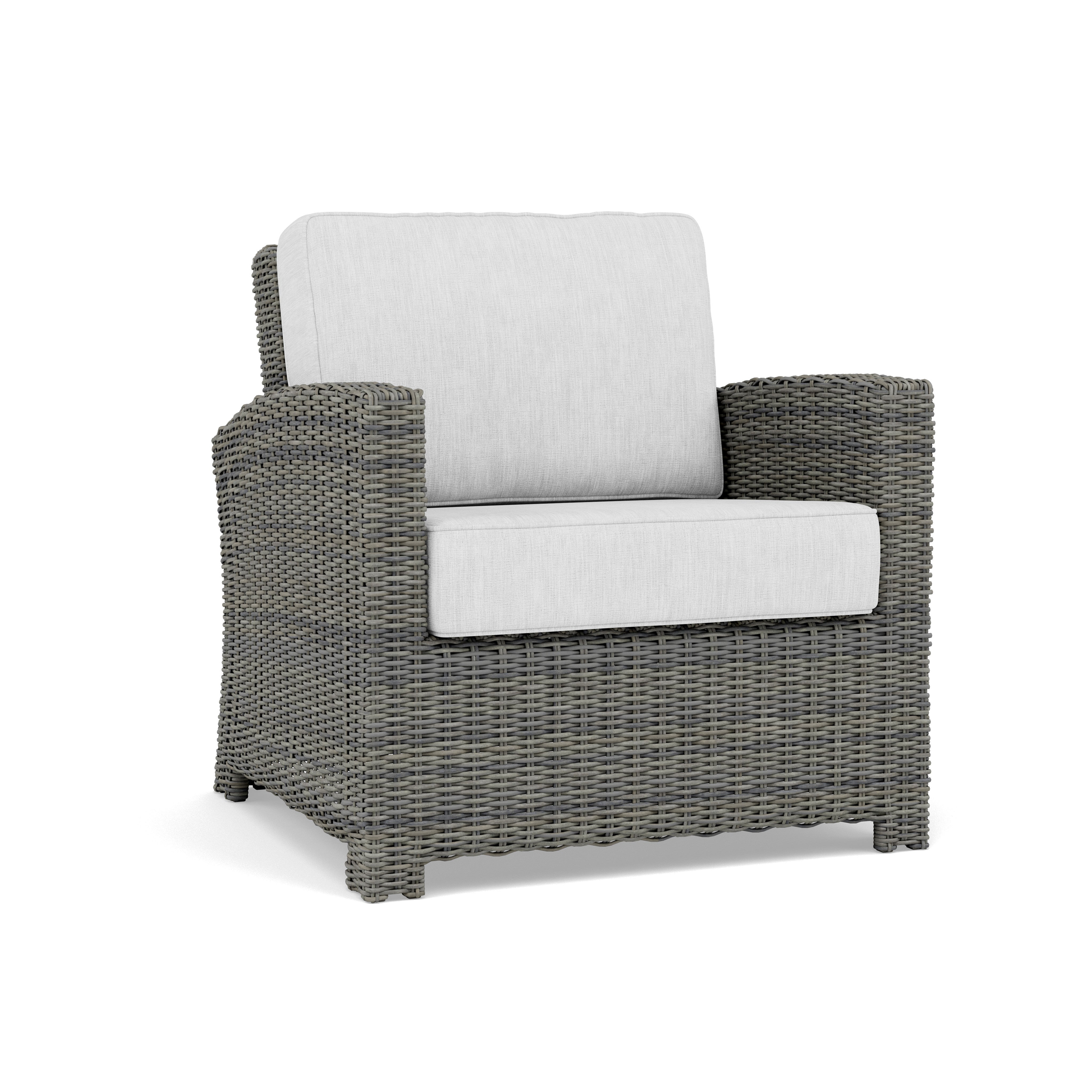 Gray wicker armchair with light cushion, suitable for outdoor or indoor seating.