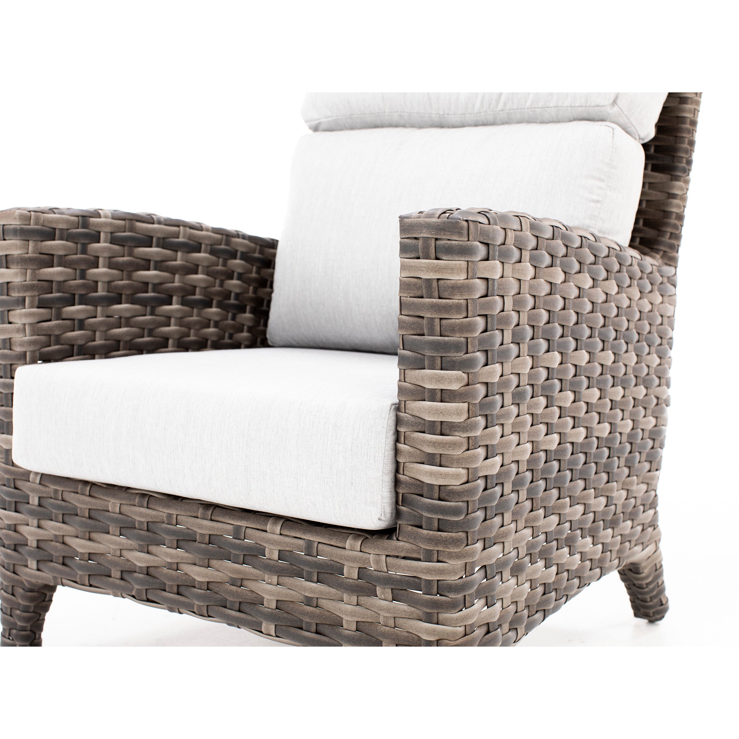 Close-up of a woven rattan armchair with light gray cushions.