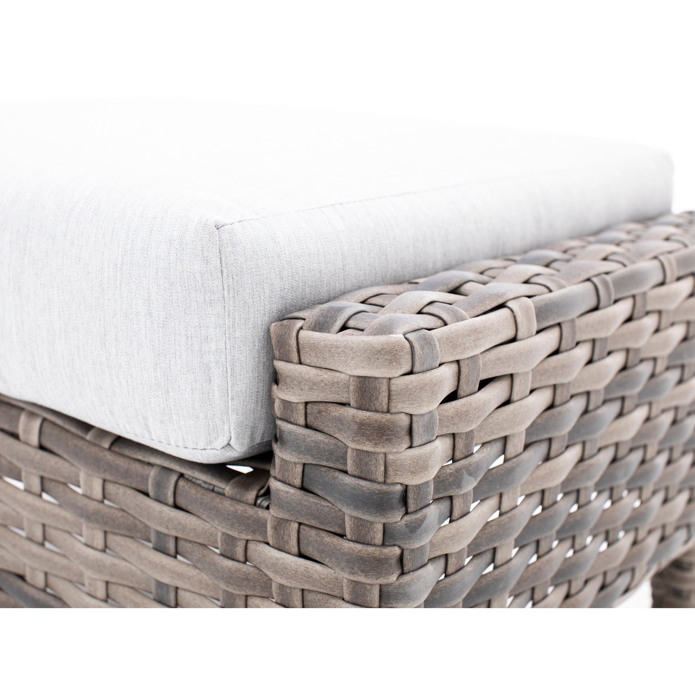 Close-up of a woven wicker furniture corner with a light gray cushion.