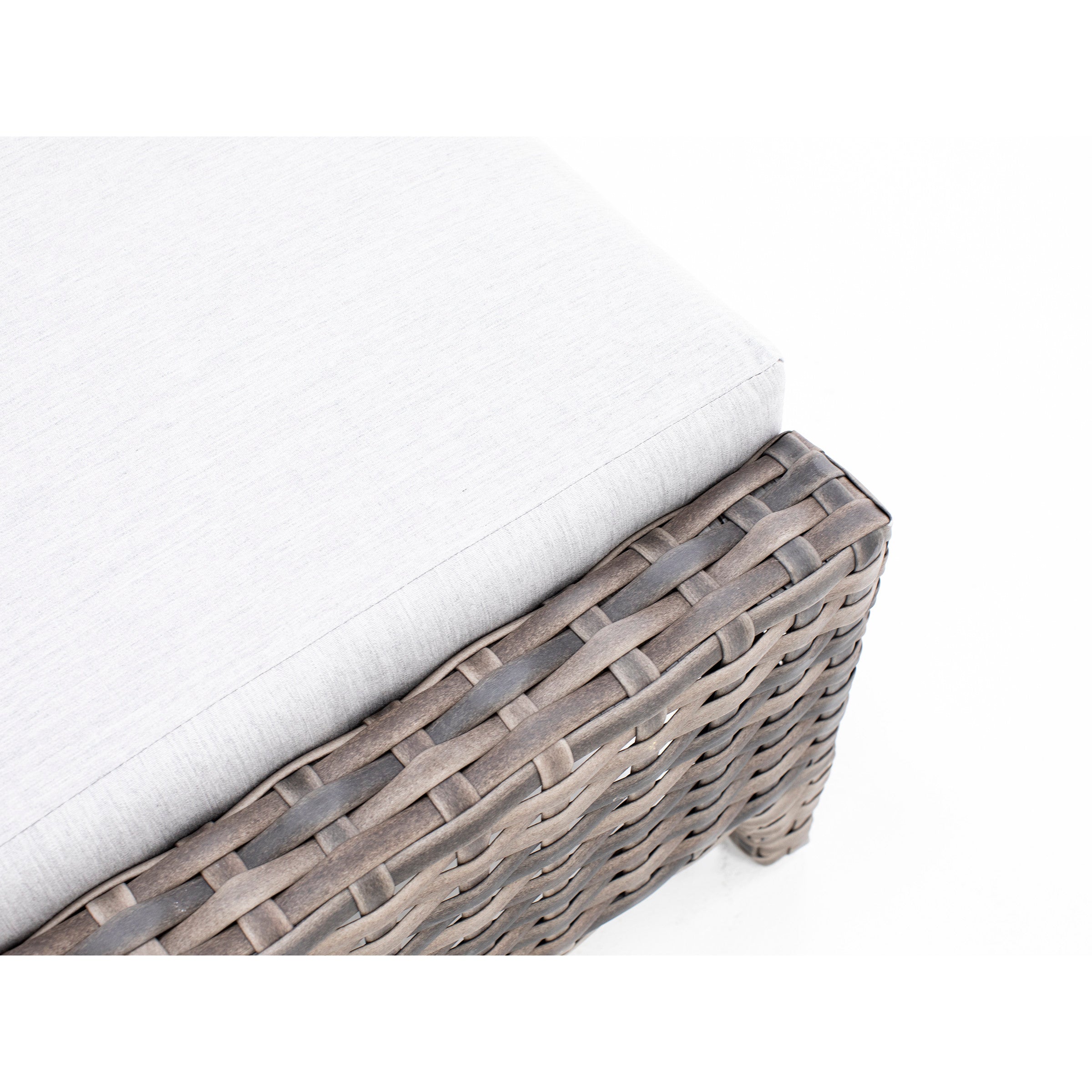 Close-up of a light gray cushion on a woven rattan outdoor furniture corner.