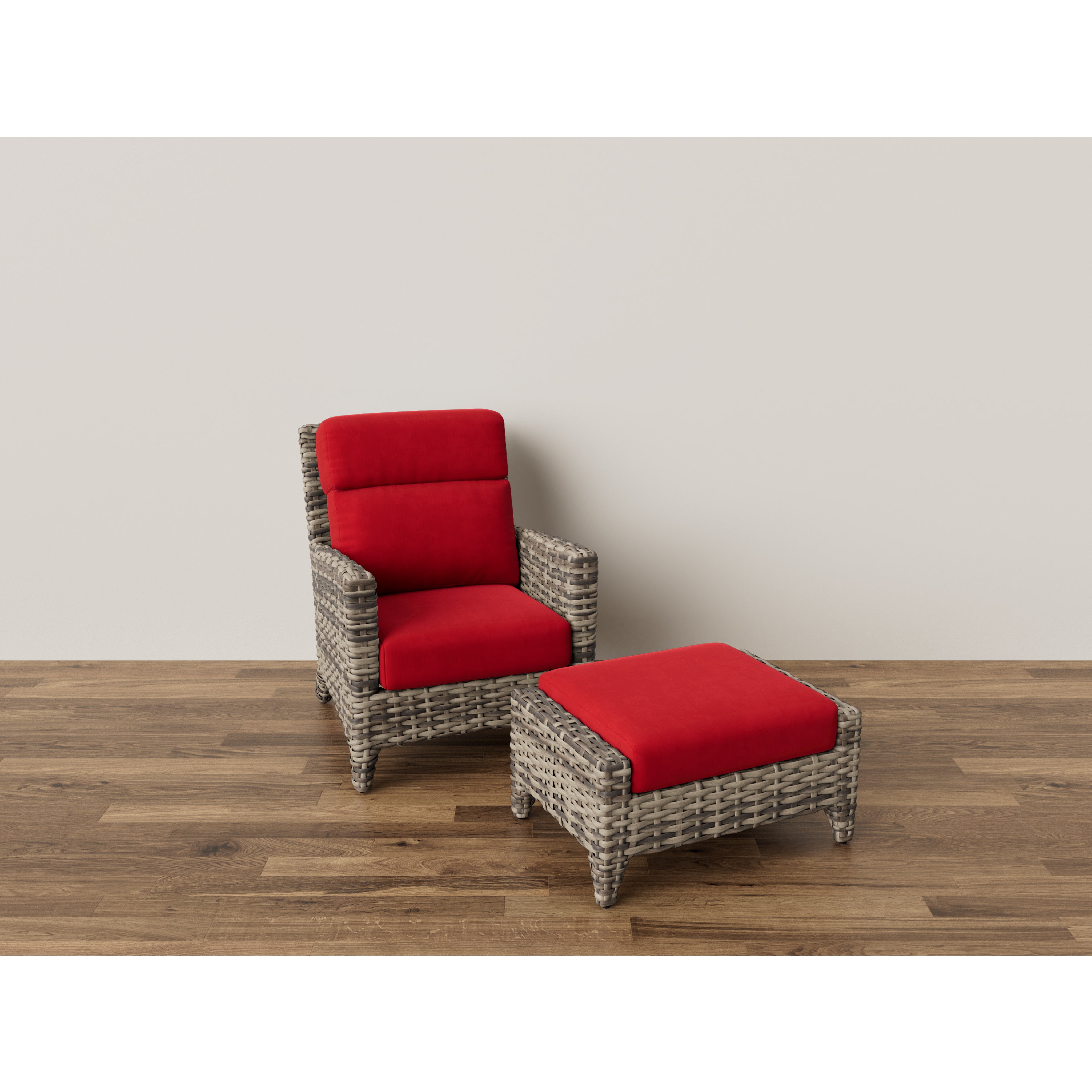 Wicker armchair and ottoman with bright red cushions on wooden floor.