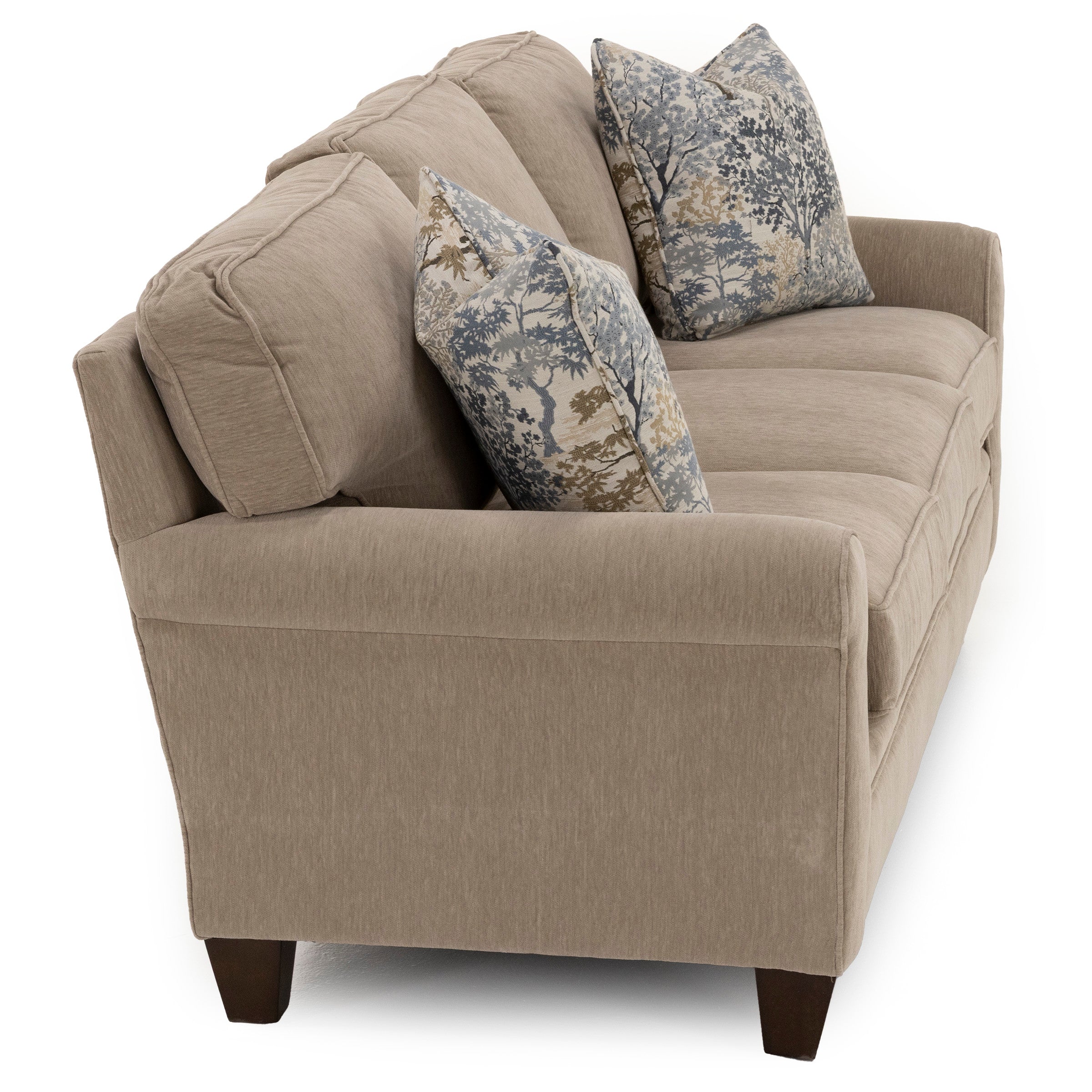 Beige sofa with two patterned throw pillows viewed from an angle.