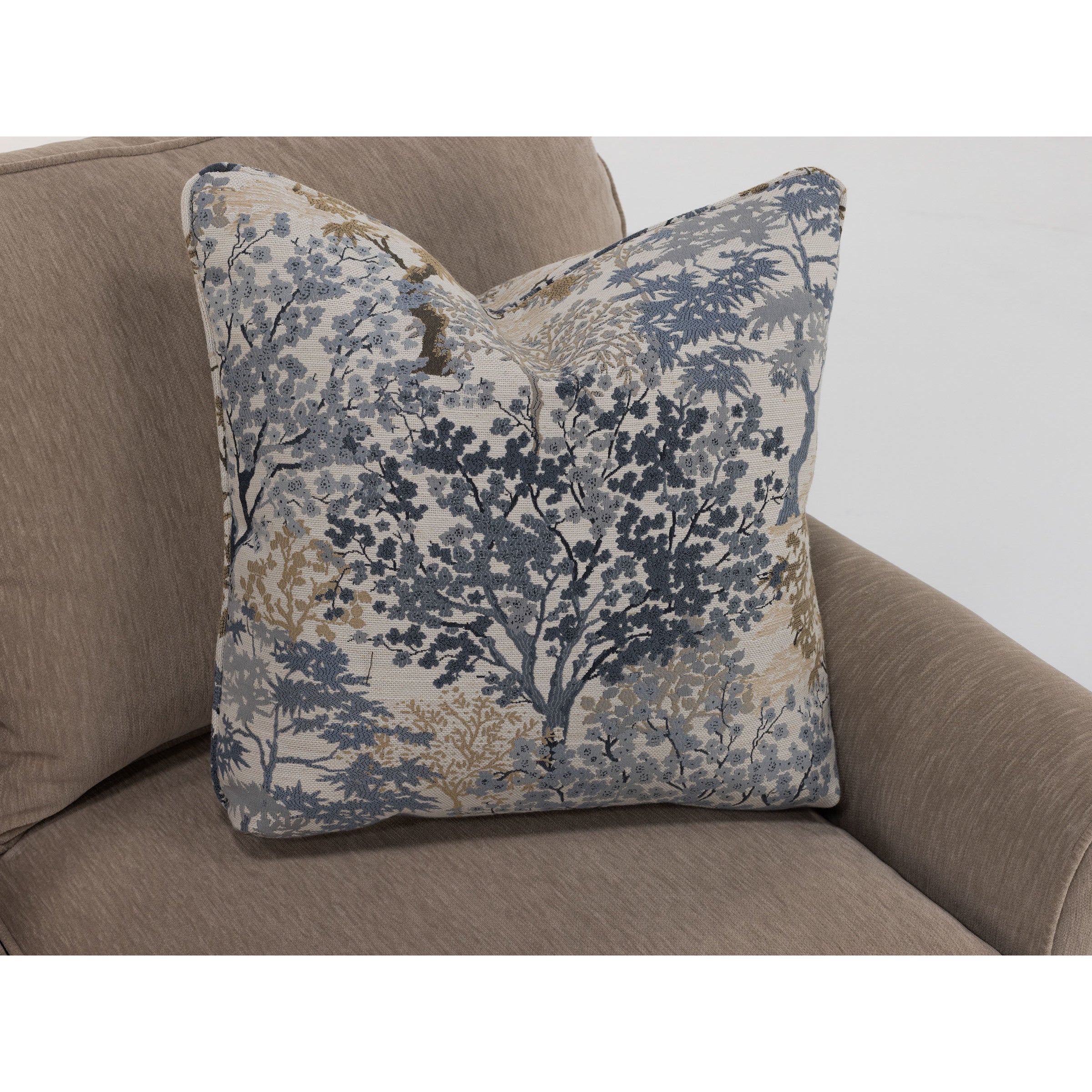 Decorative pillow with a blue and beige tree pattern on a beige sofa.