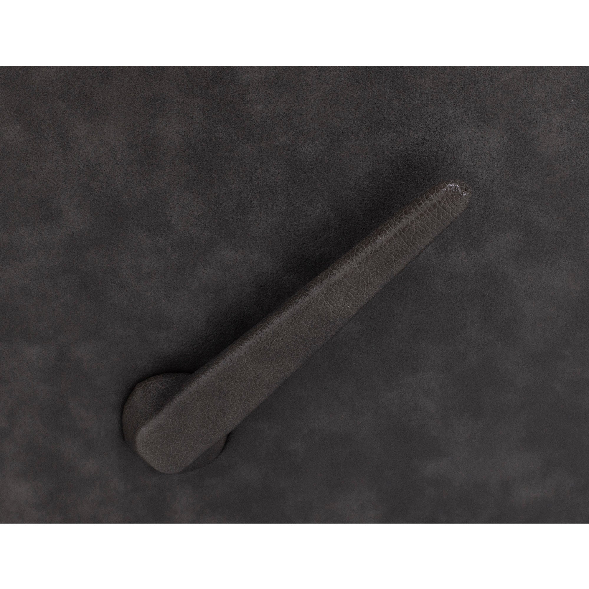 Close-up of a black textured lever on a dark surface.