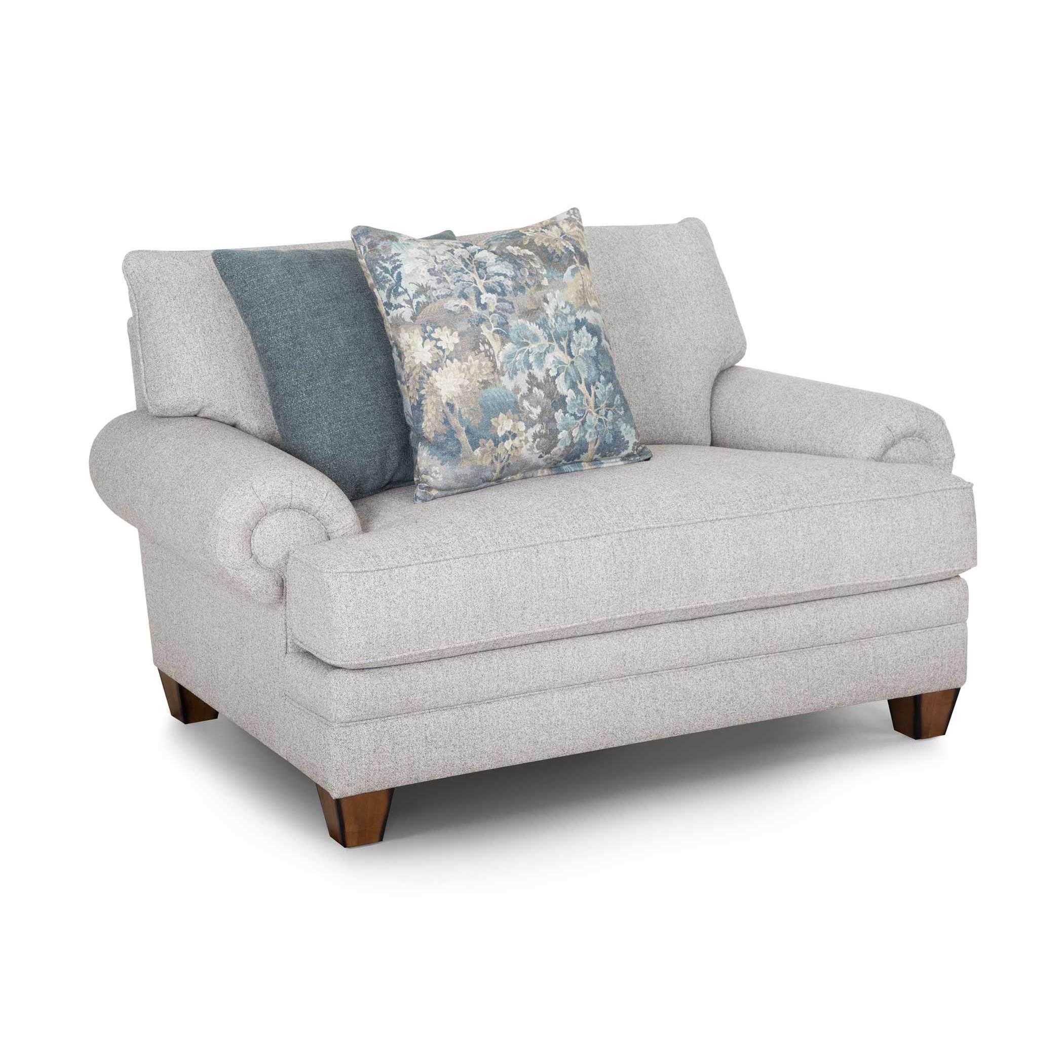 Light gray upholstered chair with two accent pillows.