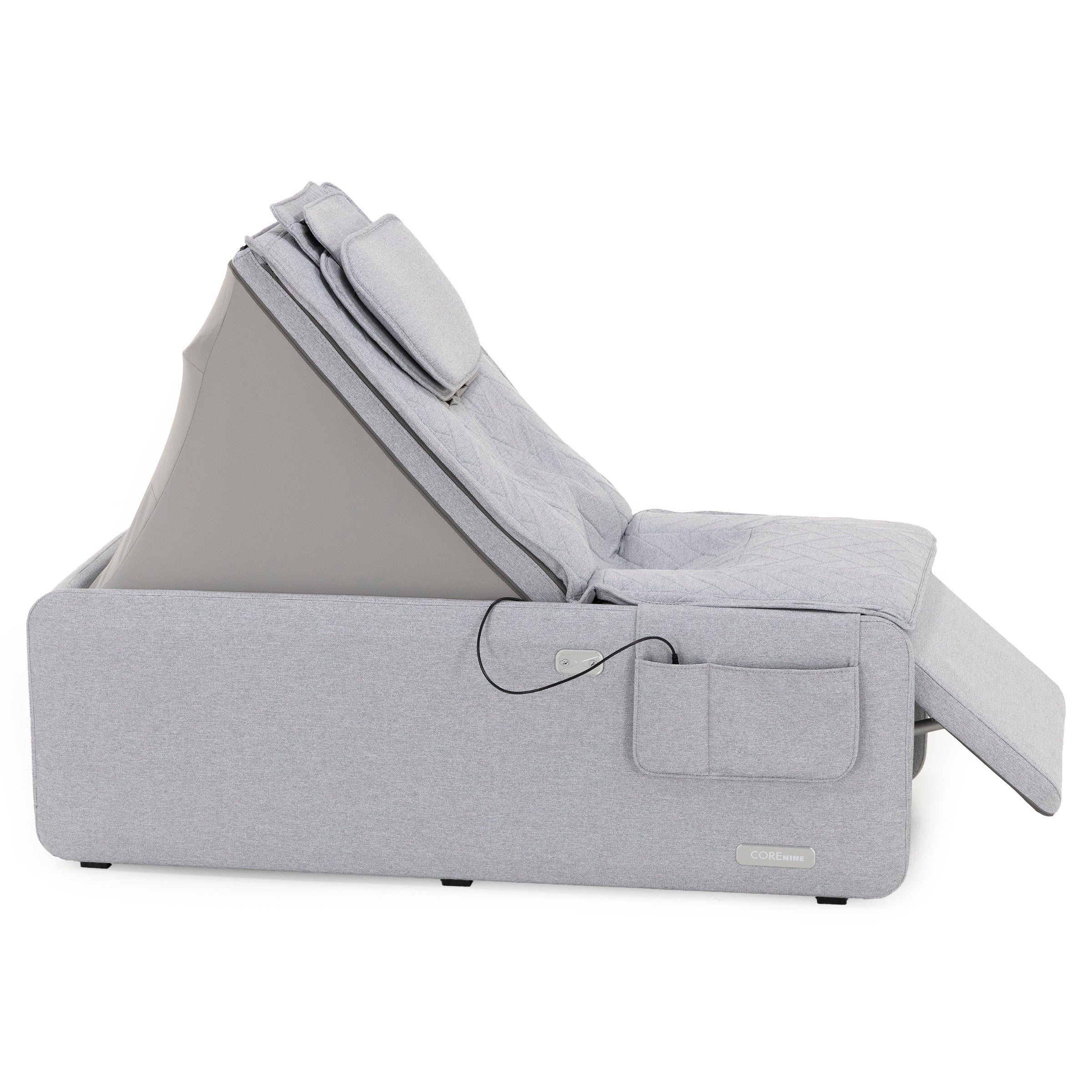Light gray adjustable reclining bed with padded headrest and side pocket.