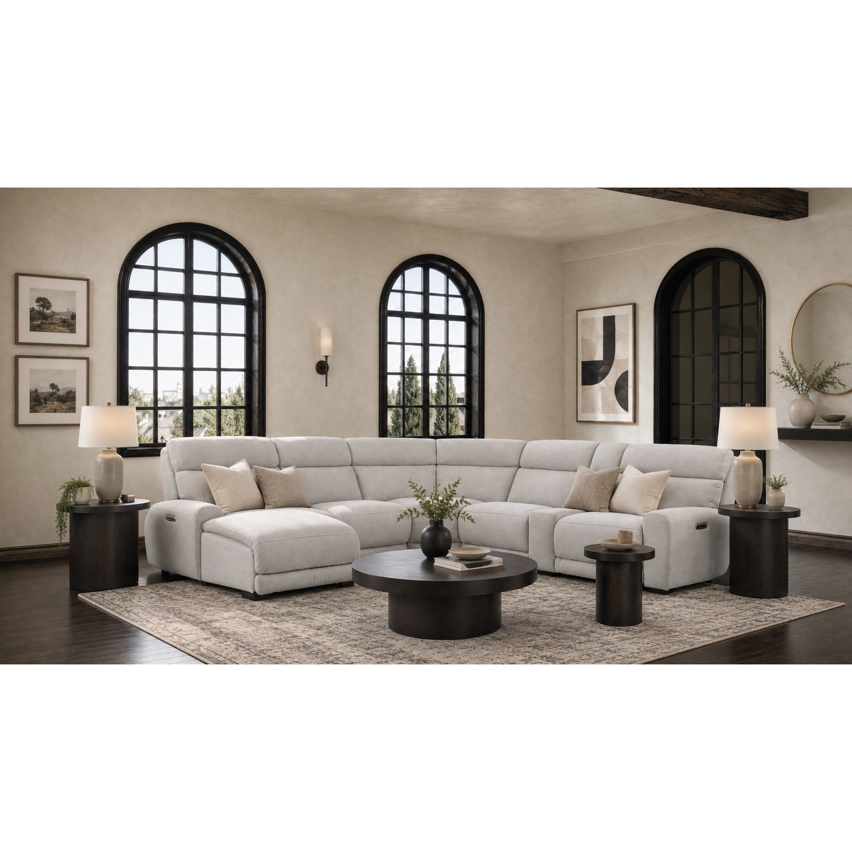 Modern living room with a light gray sectional sofa, round tables, and large arched windows.