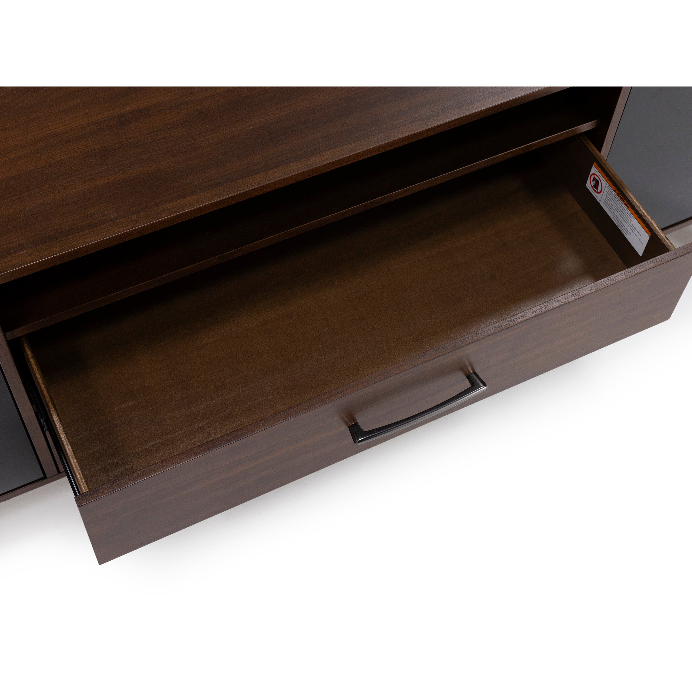 Open drawer in a dark wood cabinet with a curved metal handle.