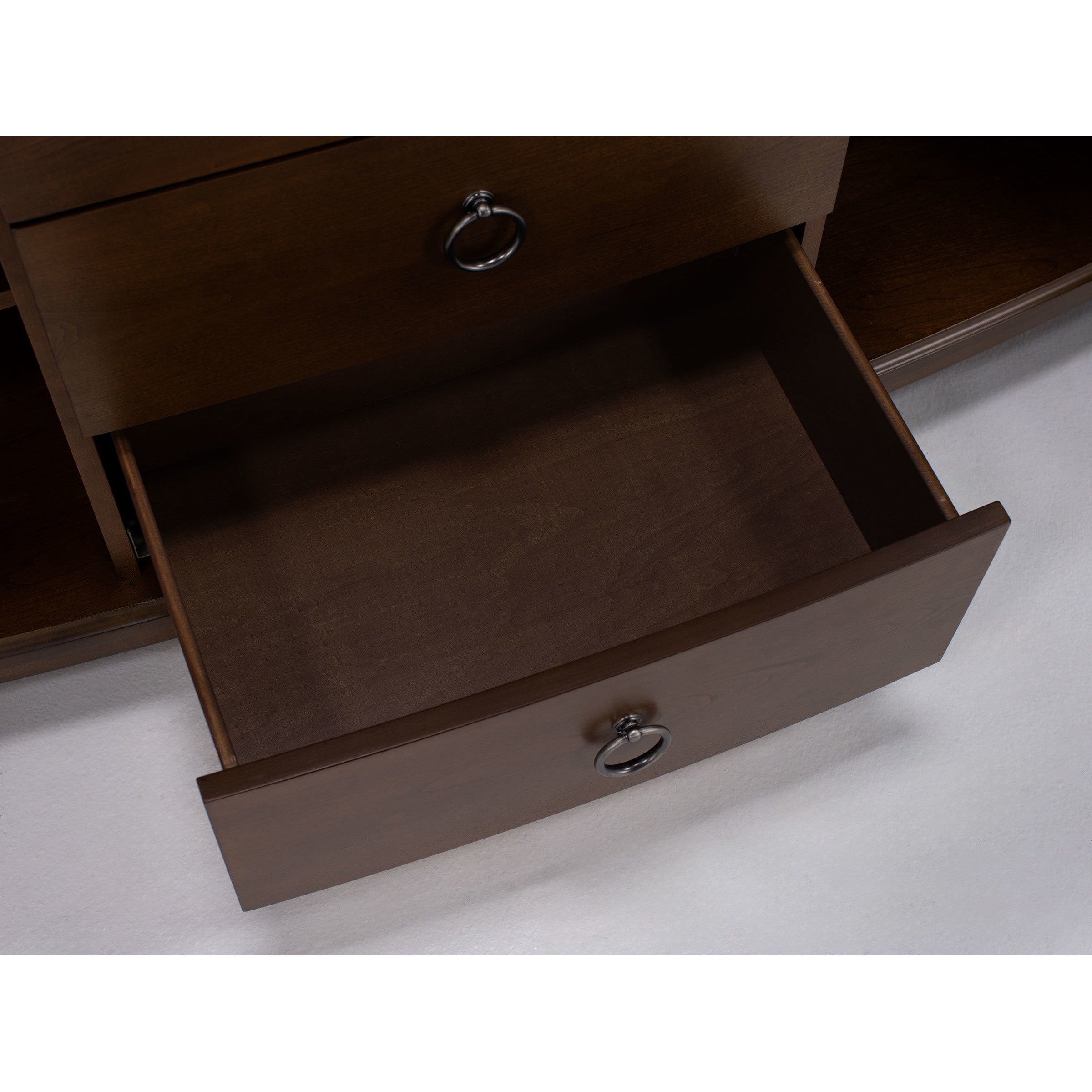 Open, empty wooden drawer with a round metal pull handle.