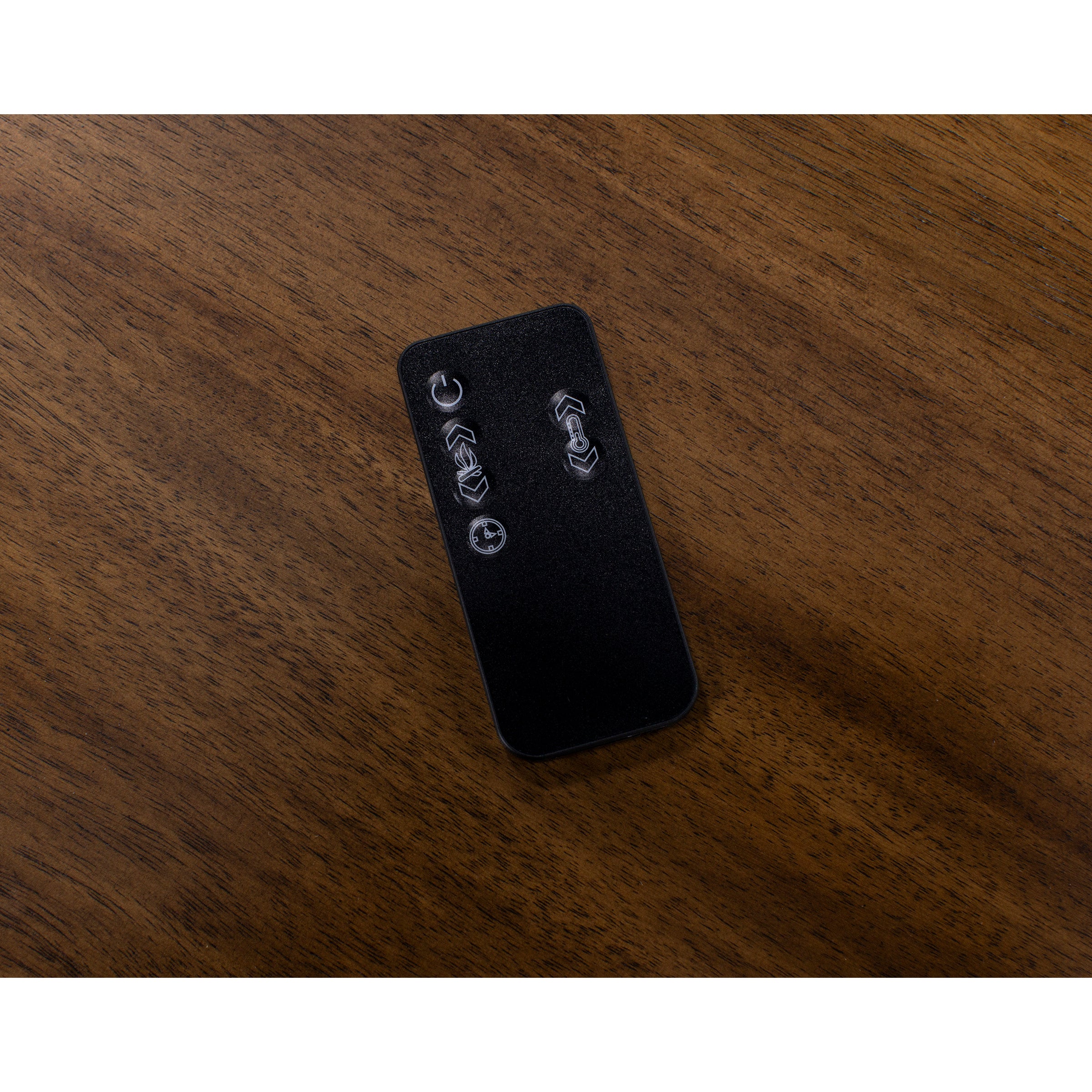 Black remote control with silver buttons on a wooden surface.