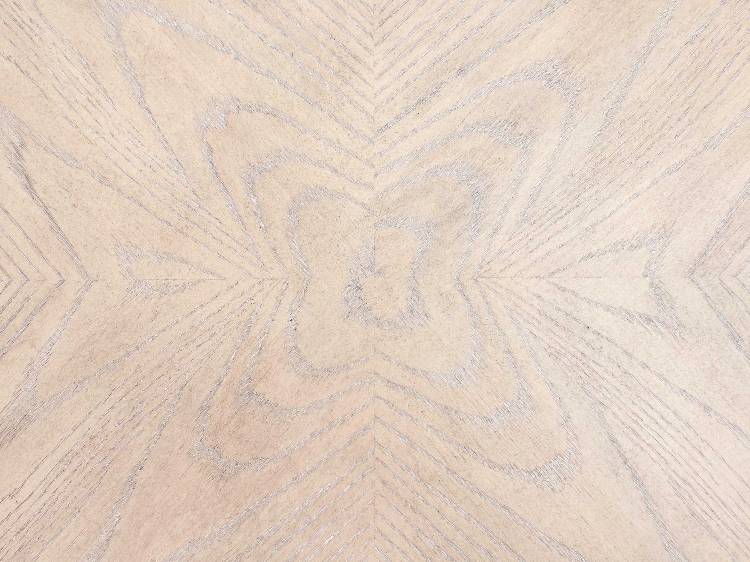 Light wood surface with a geometric, symmetrical grain pattern.