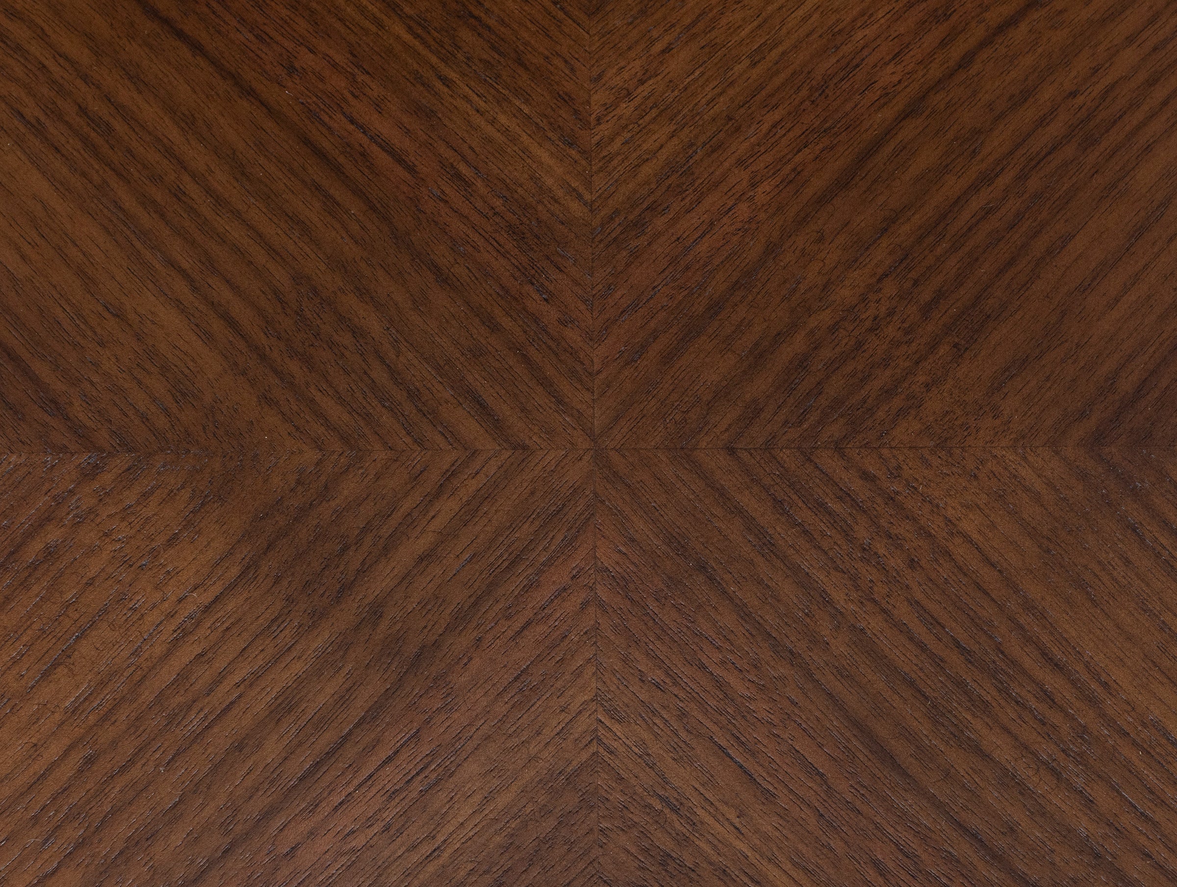 Close-up of brown wood texture with chevron pattern, showing grain details.