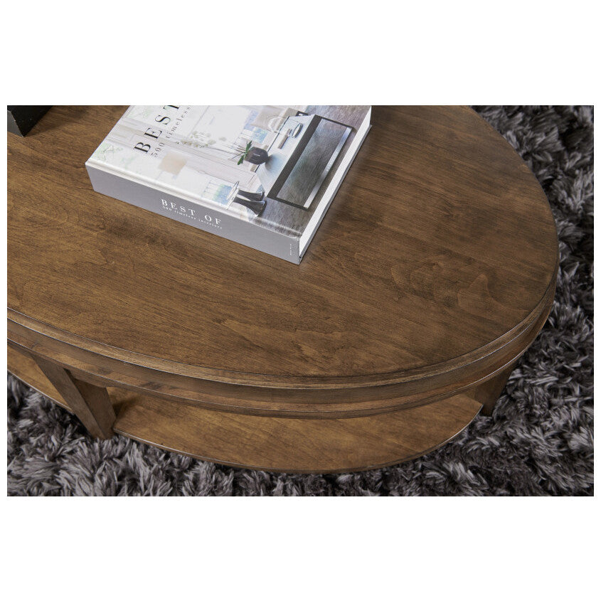 Oval wood coffee table with a book on top, on a gray textured rug.