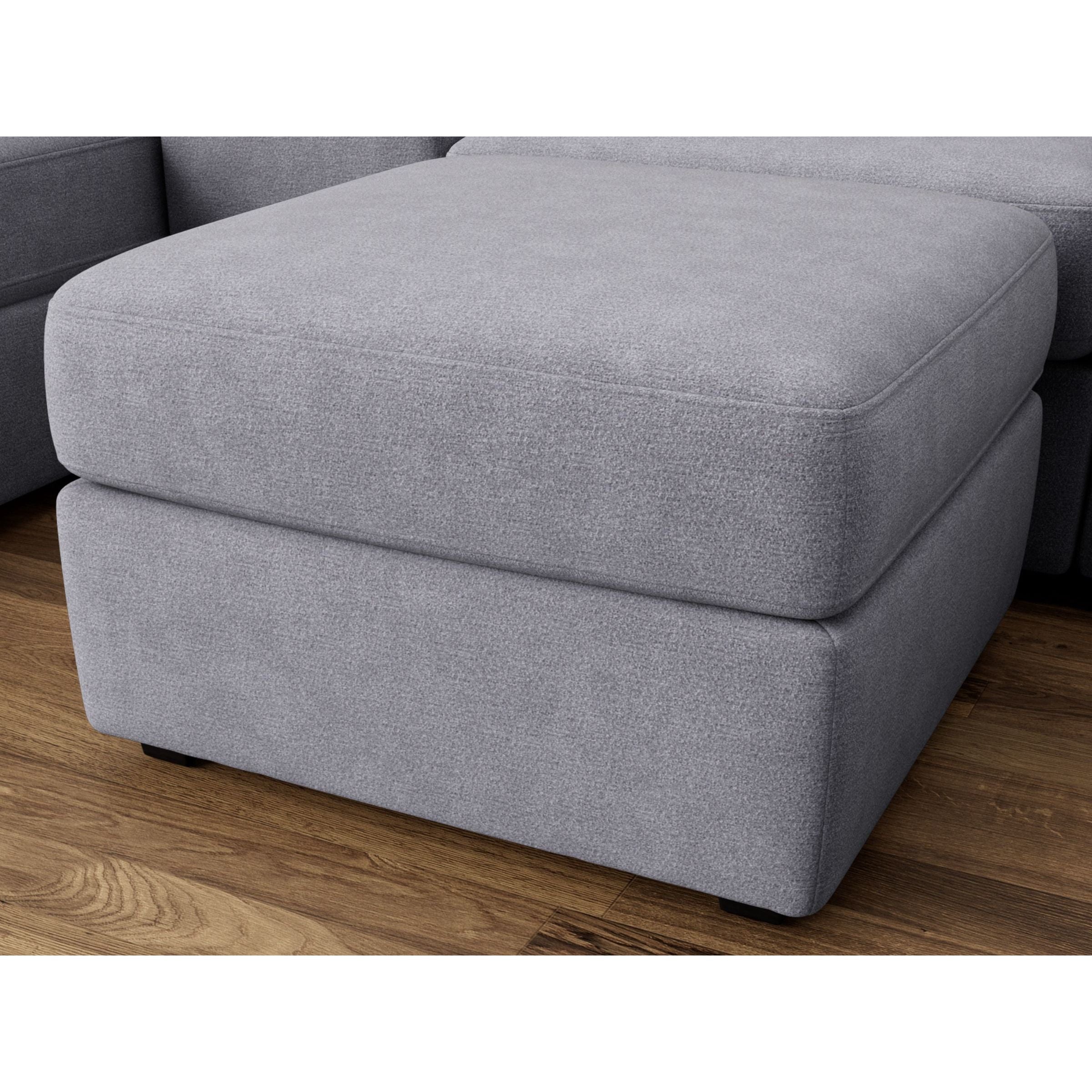 Gray upholstered ottoman with square shape on wood floor.