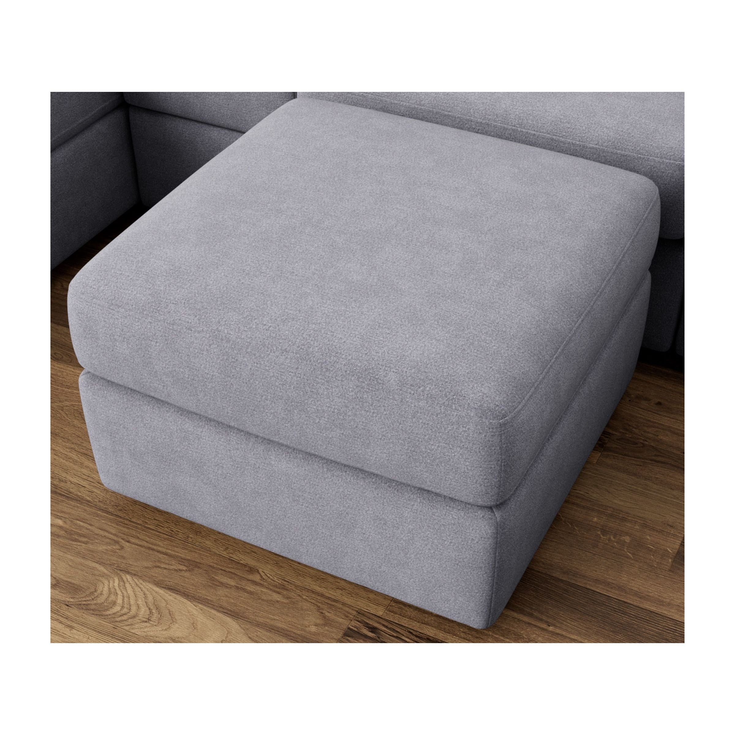 Square gray fabric ottoman on a wood floor.