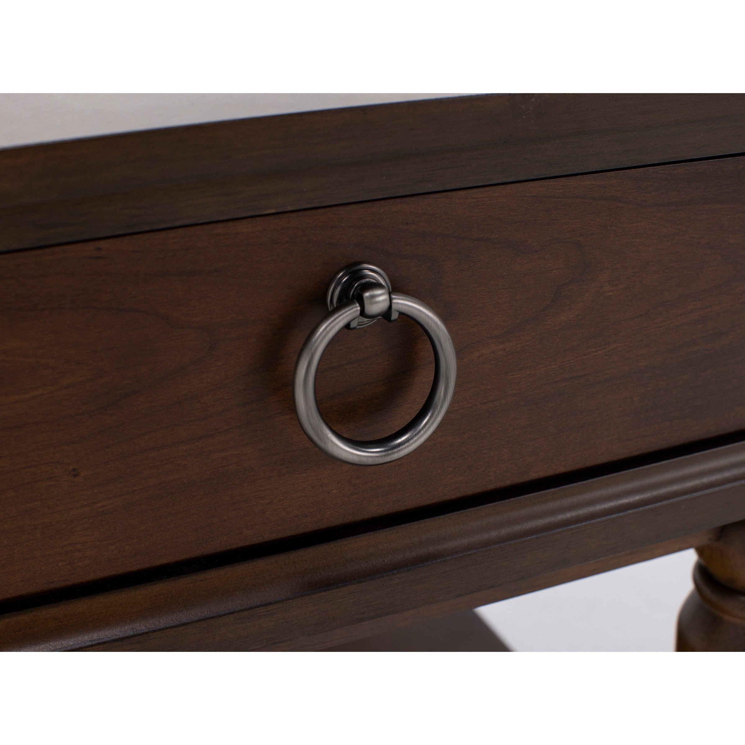 Close-up of a drawer with a metal ring pull handle on a dark wood finish.