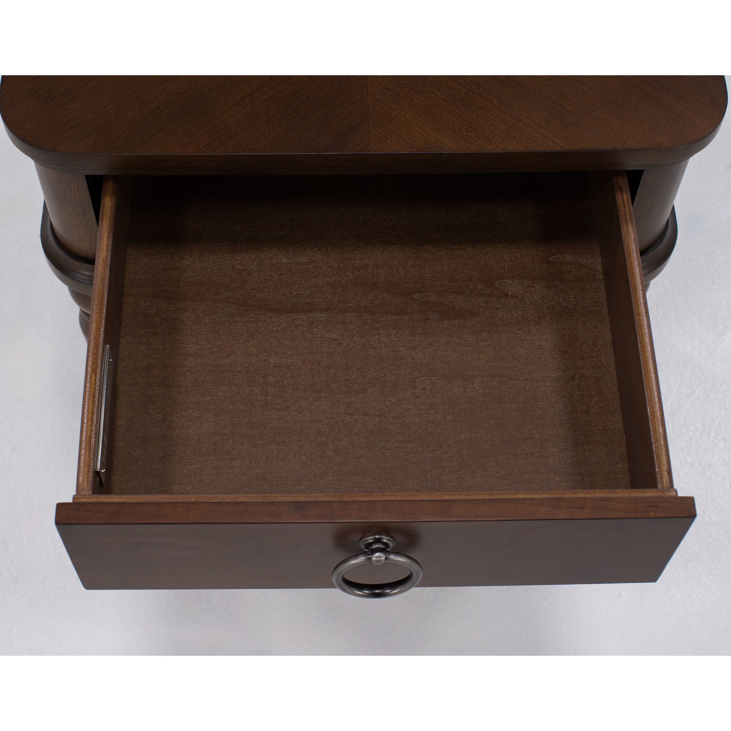 Top view of an open, empty wooden drawer with a metal ring handle.