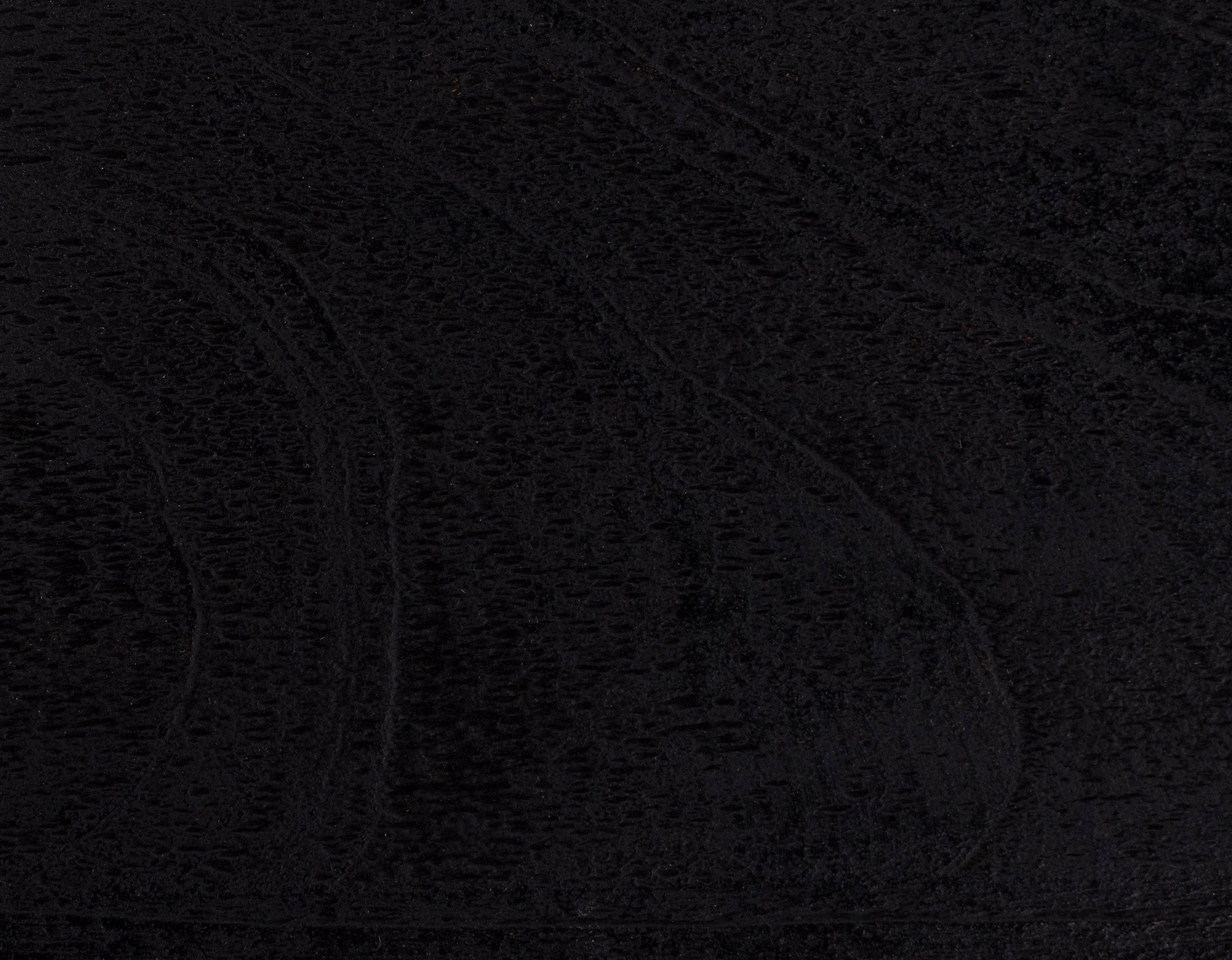 Black wood surface with visible textured grain pattern.