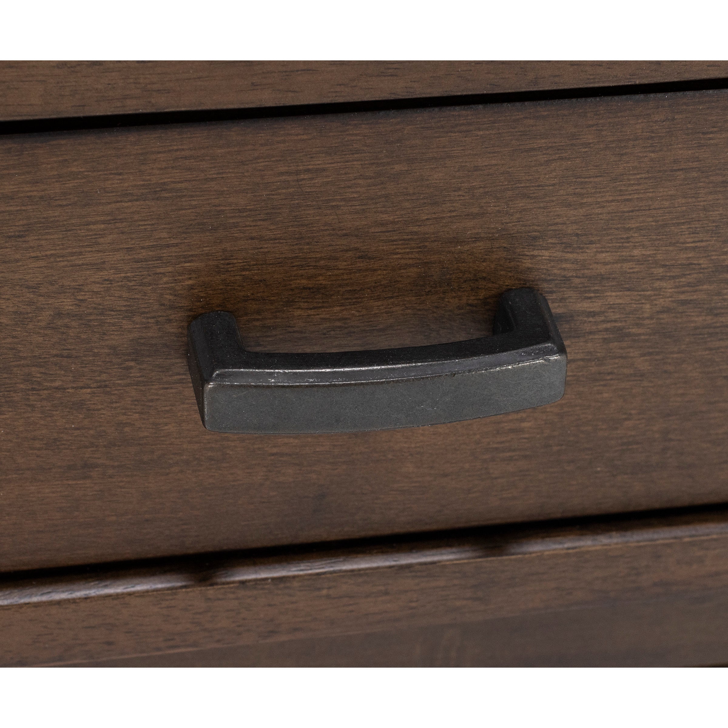 Close-up of a dark metal drawer handle on a wooden surface.