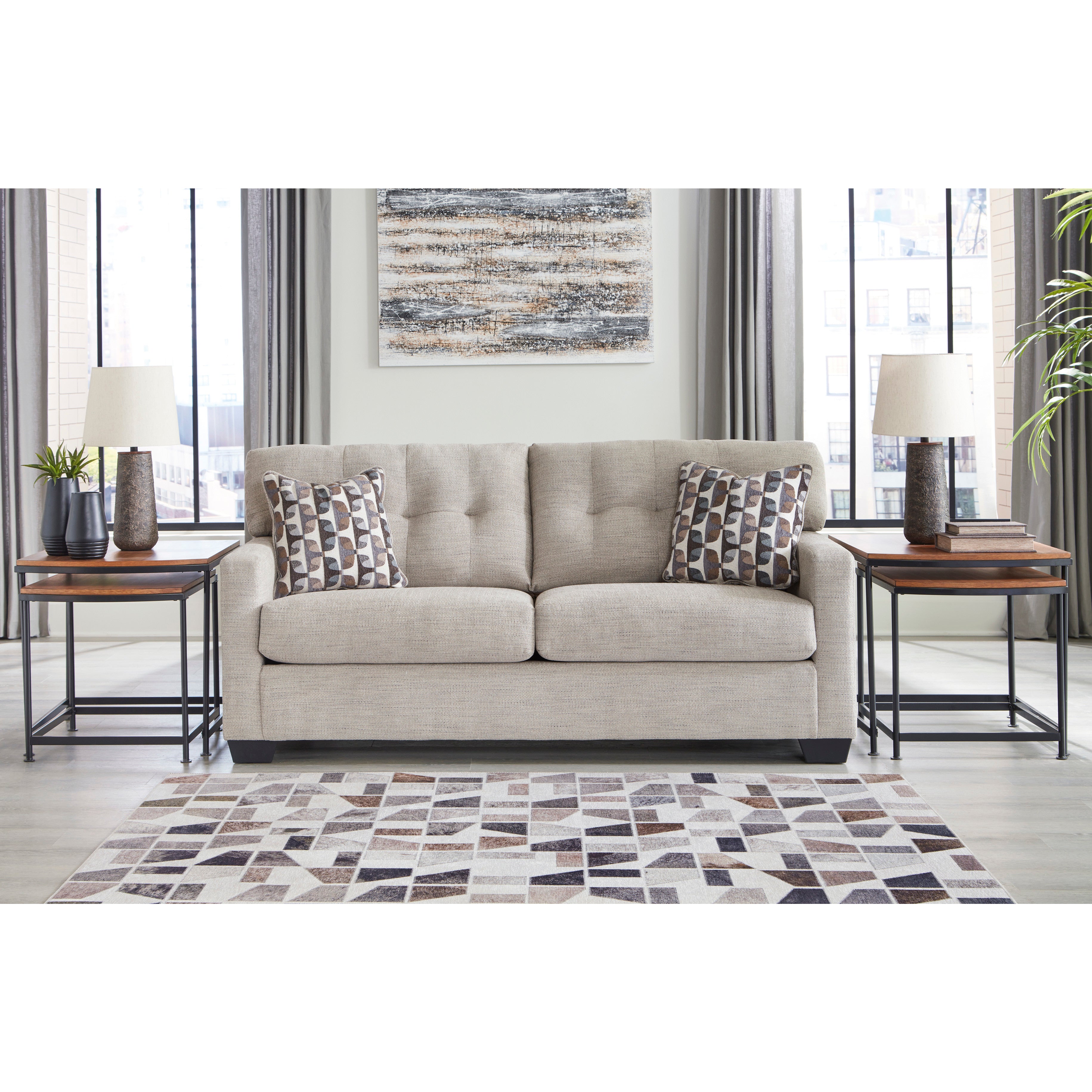 Neutral modern sofa with geometric pillows, flanked by end tables and lamps in a bright living room.