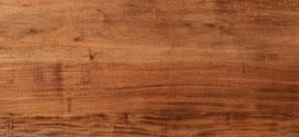 Close-up of a smooth, medium-brown wood surface with natural grain patterns.