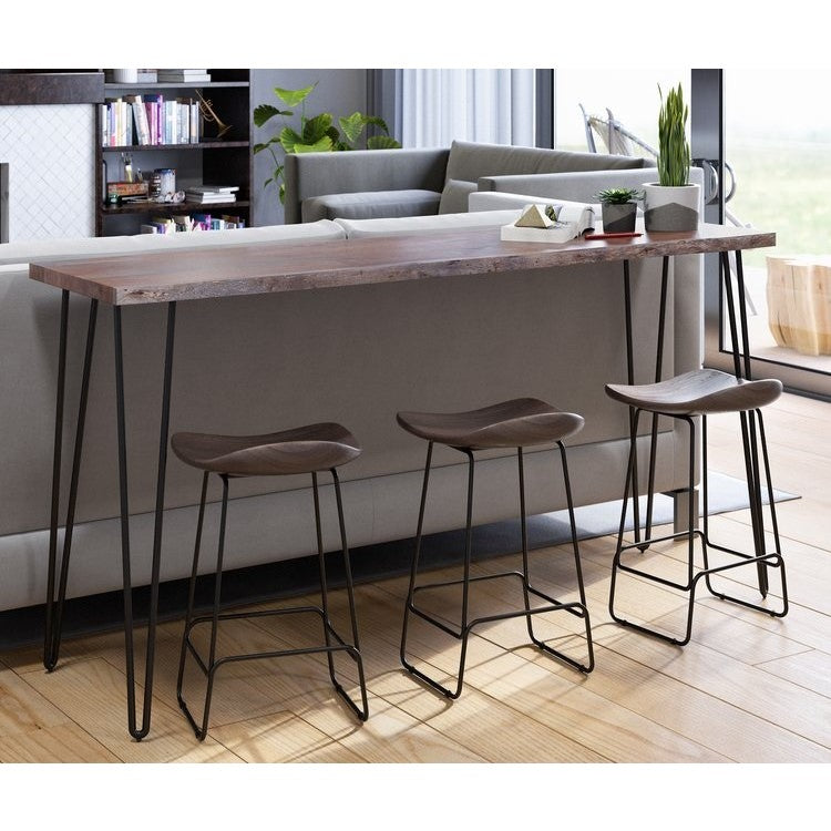 Three modern bar stools at a wooden counter behind a beige sofa in a bright living room.