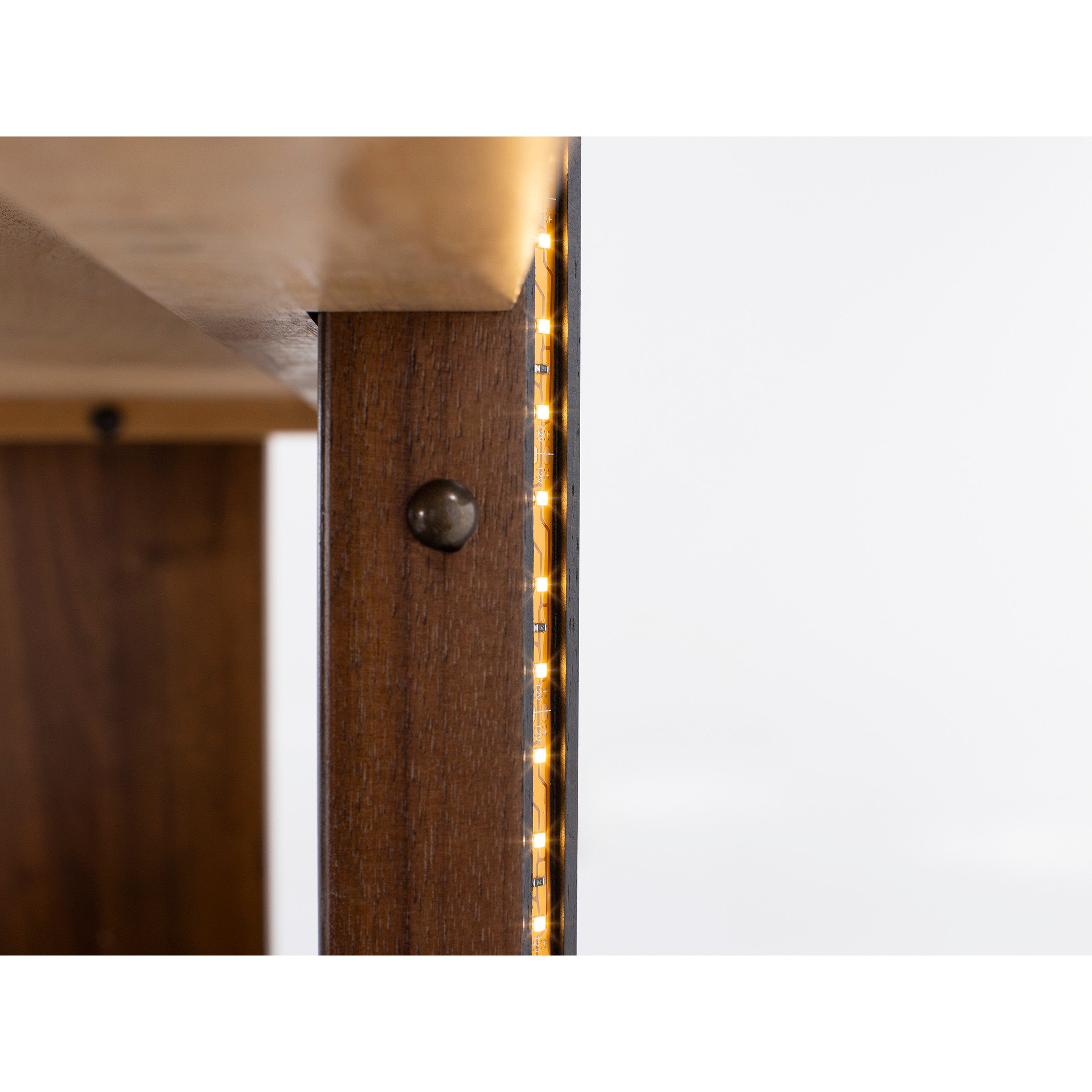 Close-up of LED strip lighting on a wooden furniture edge.