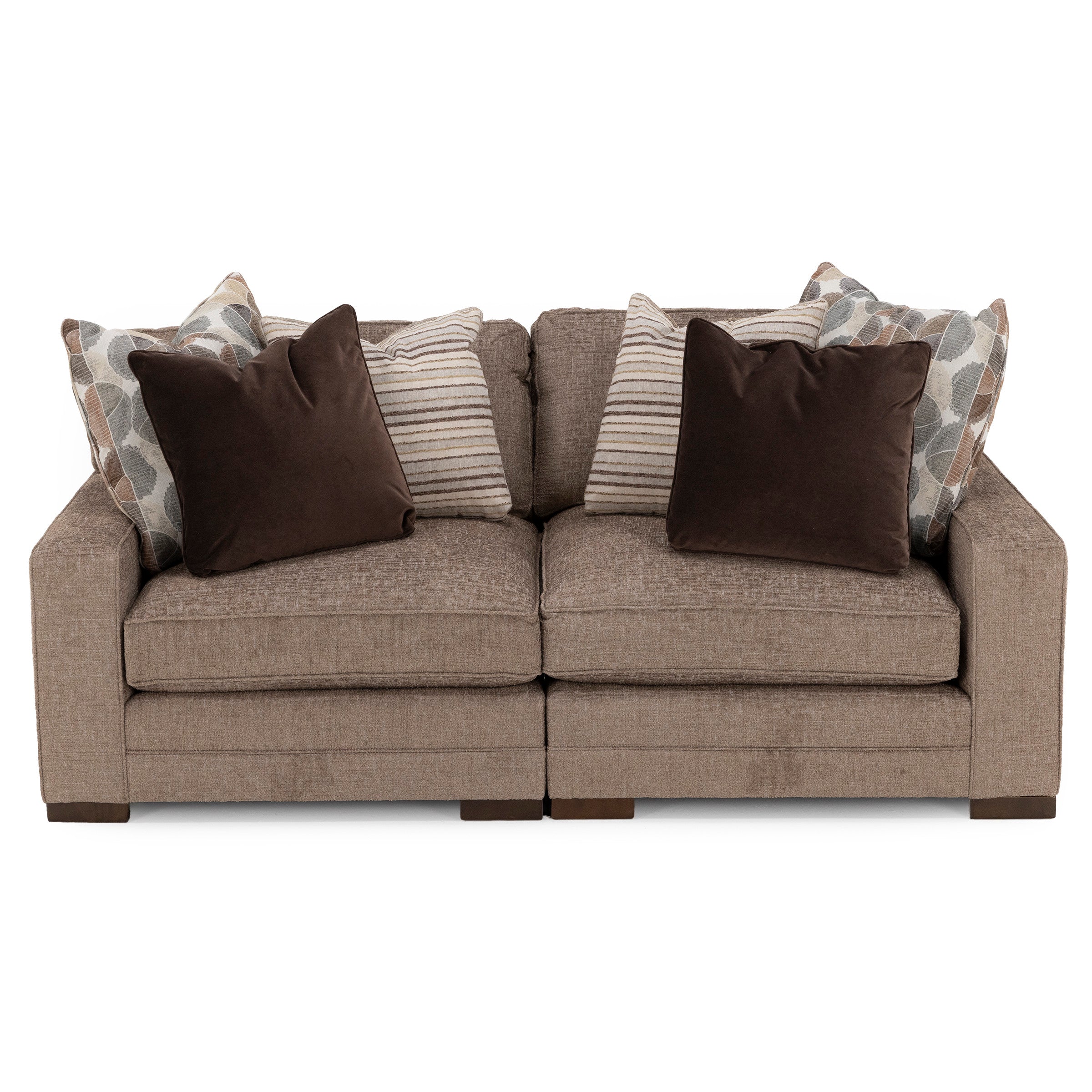 Beige upholstered sofa with four decorative pillows in brown, striped, and leaf patterns.