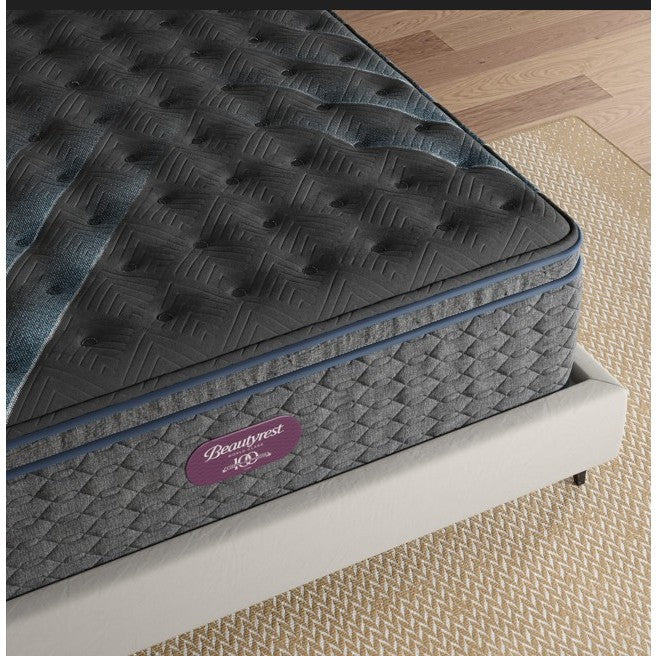 Closeup of a Beautyrest mattress with black and gray quilted top on a beige bed frame.