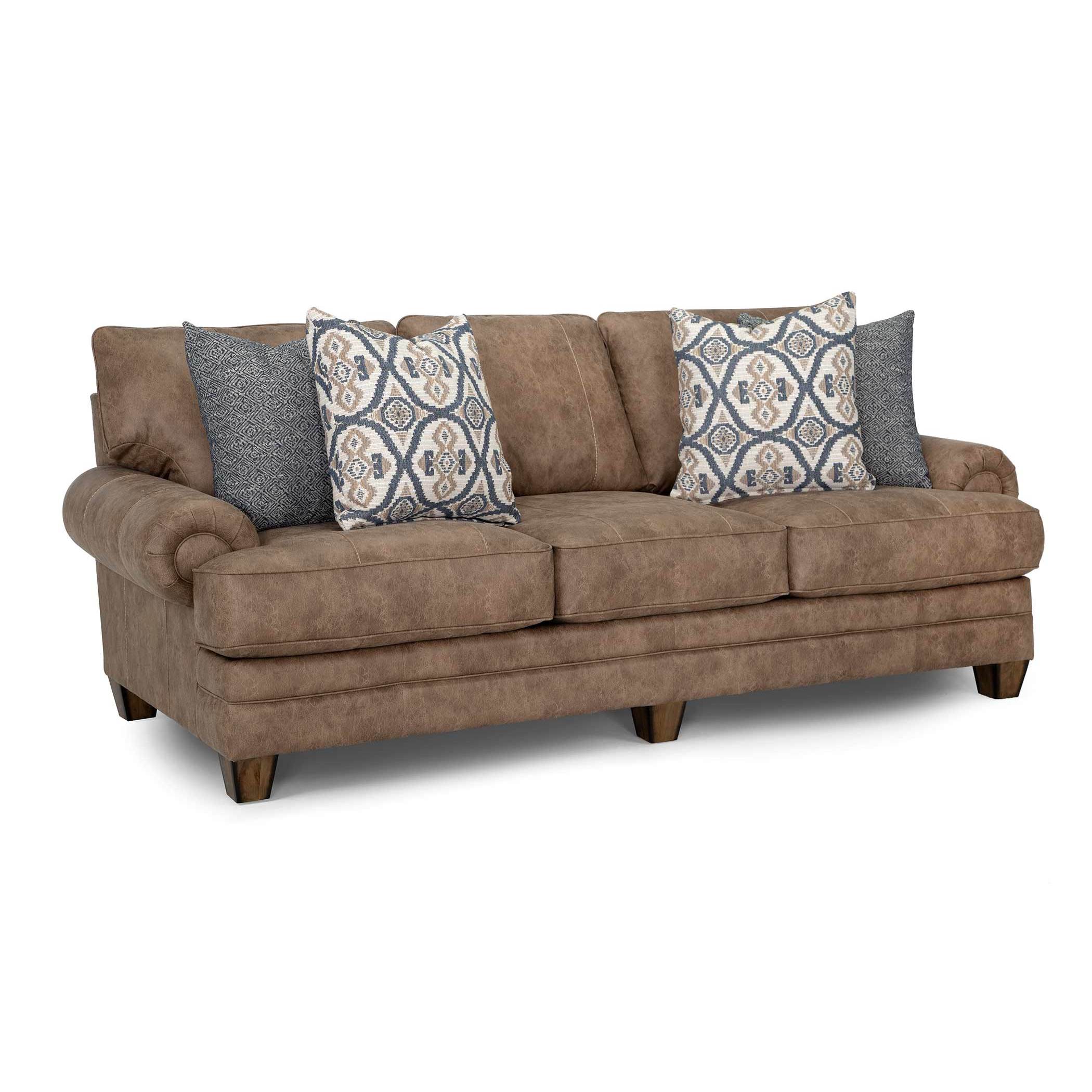 Brown sofa with rolled arms and four decorative pillows in blue and tan patterns.