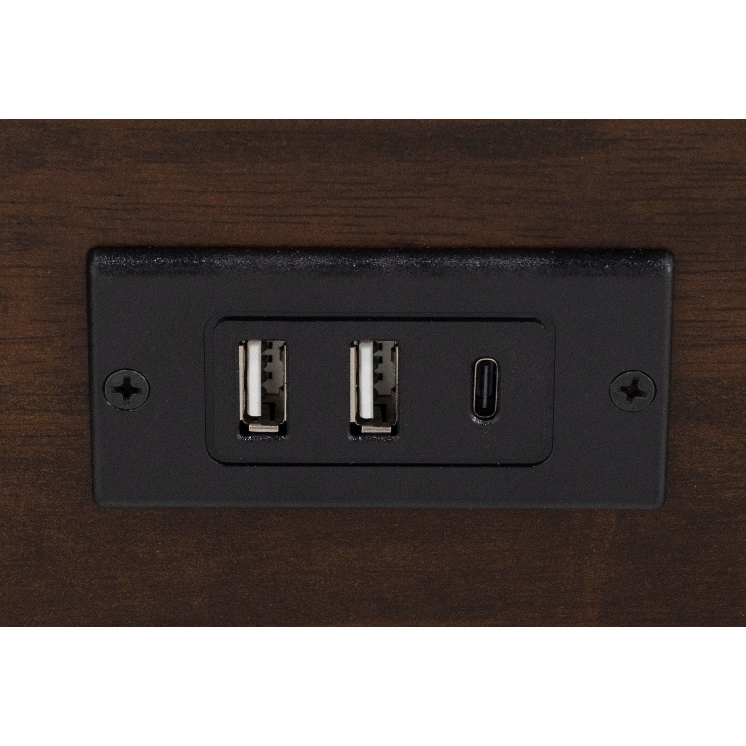 Closeup of a black outlet plate with two USB-A ports and one USB-C port on a wood surface.