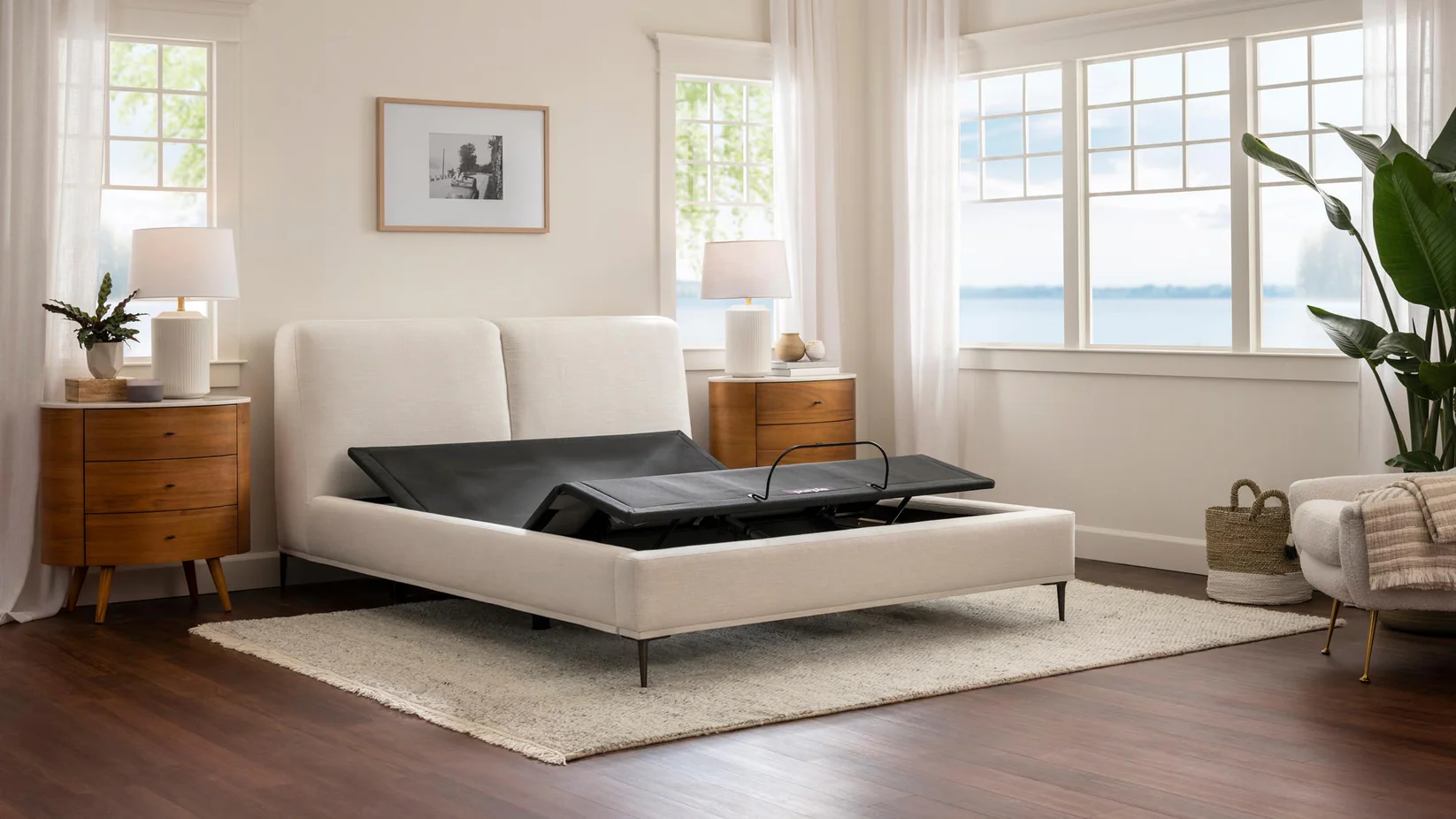 White bed with black mattress in a bright bedroom with large windows.